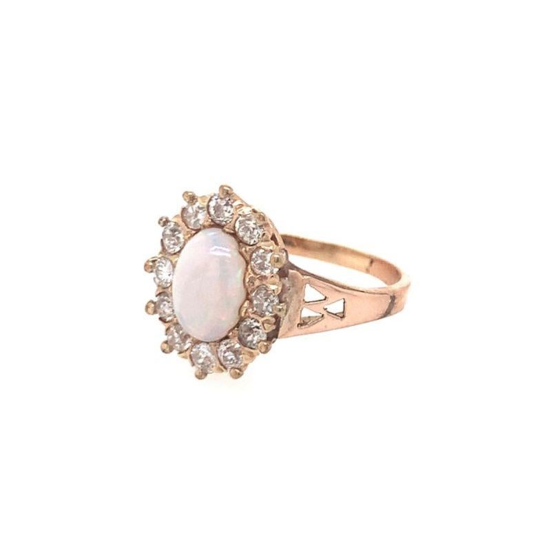One white opal and diamond 14K yellow gold ring featuring one oval cabochon cut white opal weighing approximately 1 ct. surrounded by old European cut diamonds weigh approximately 0.75 ct. in total. Mesmerizing play of color shown upon the