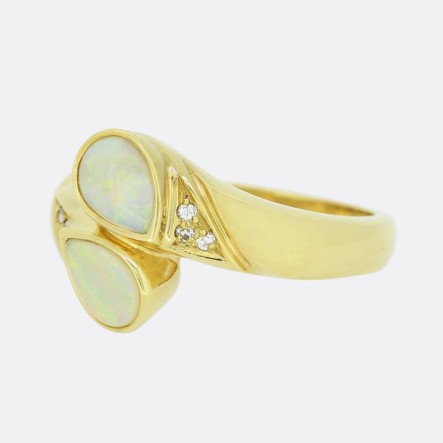 This is an 18ct yellow gold white opal and diamond abstract ring. Each central opal is rub-over set, pear shaped and has an excellent white body of colour. These focal opals are highly complimented by the two trios of round cut natural diamonds