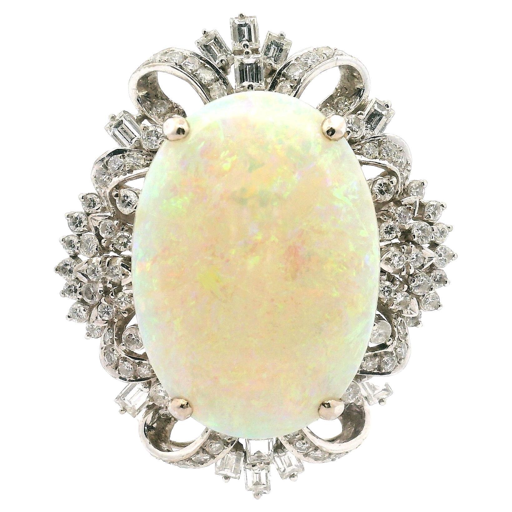 Grande opale bianco incastonato in un bouquet a nastro in oro bianco, ornato di diamanti. 
Anello Can che può essere trasformato in un ciondolo. Composto da:

Opale bianco 26,84 mm X 19,34 mm X 7 mm

Diamanti rotondi e a baguette di circa 2,79