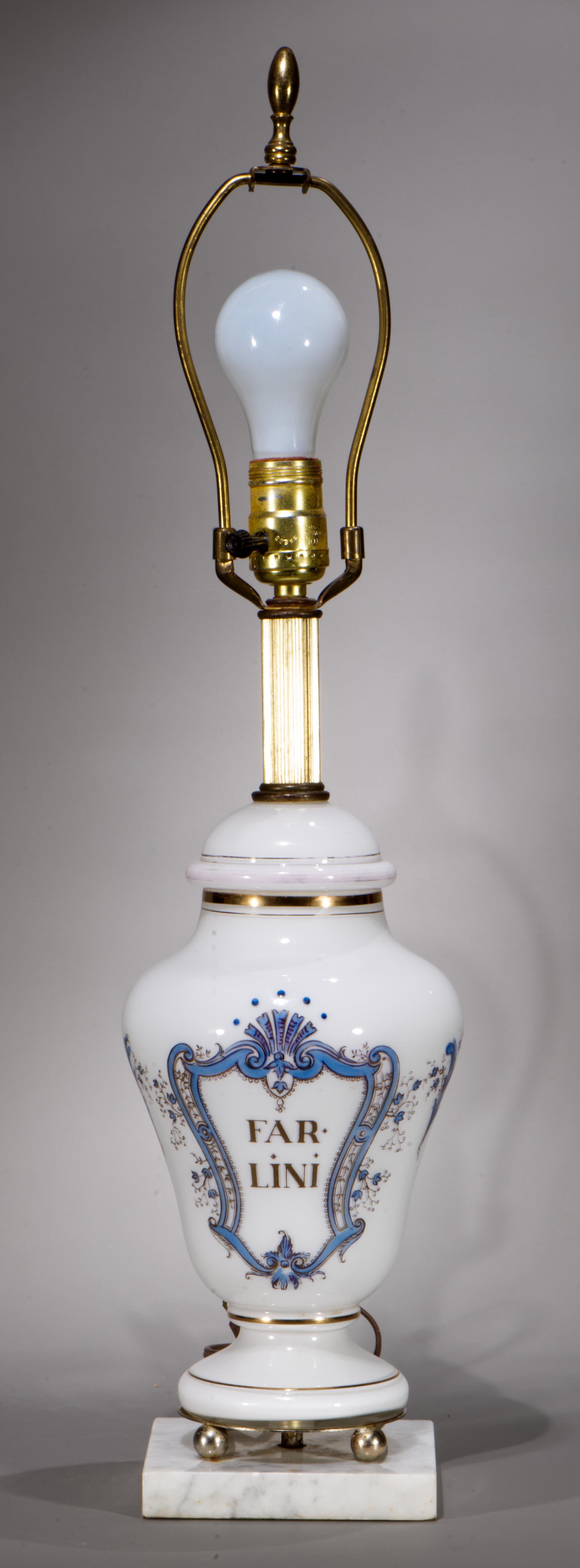  Vintage white opaline glass jar lamp features a traditional blue and gold decor with the lettering inside of a framed medallion surrounded by small floral garlands and scrolls. The text reads 