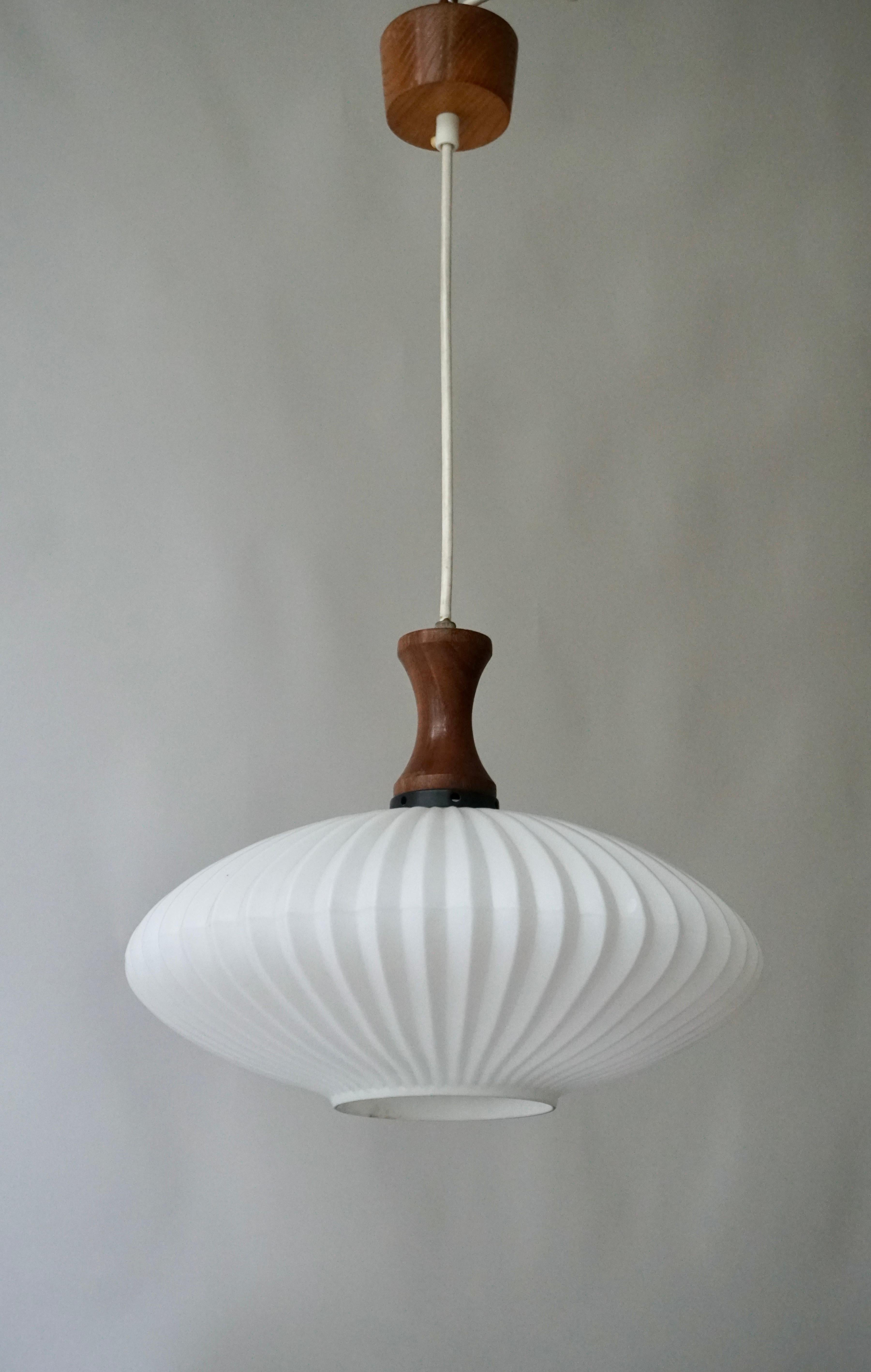 Pendant light in white milk glass oval ball lamp with ton sur ton 'stripe' motif in the glass & a teak wooden drop. Also called UFO lamp.Beautiful because of its simplicity, this sleek glass hanging lamp.Considering its age still in very good
