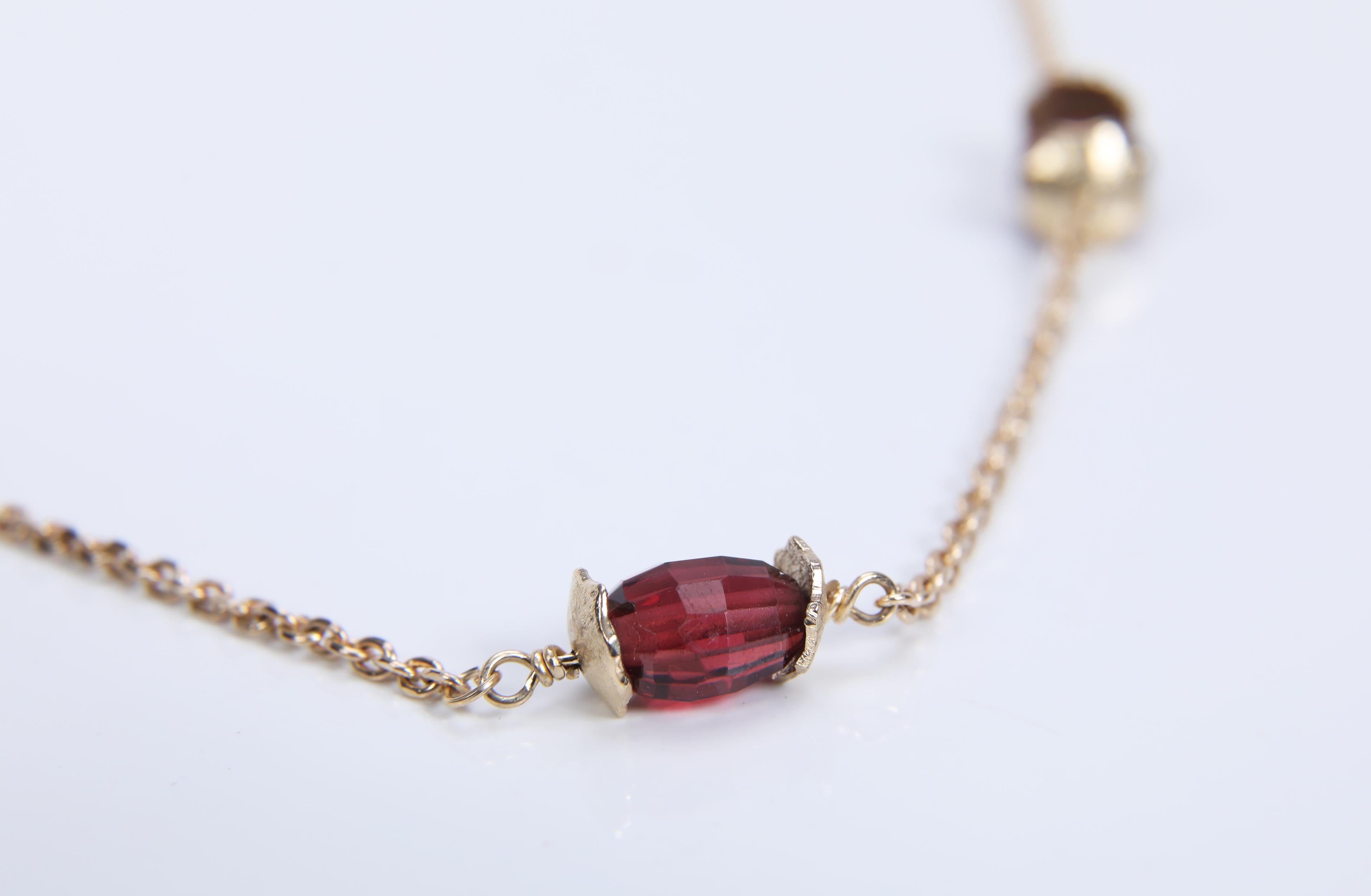 A choker necklace of 14ky yellow gold chain enhanced by faceted ovals of Almandine garnets capped by our textured gold spacers. The necklace is finished with a White Orchid Studio artisan logo clasp in 14kt yellow gold. 16.5