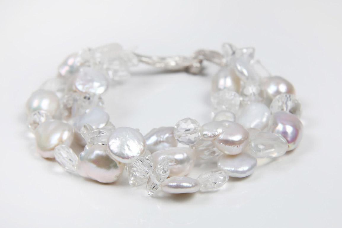 A three-strand bracelet of white baroque and coin freshwater pearls, three shapes of clear crystal quartz, and rainbow moonstone.  The bracelet comes together with our artisan-crafted vanilla bean clasp in 925 sterling.  8.5