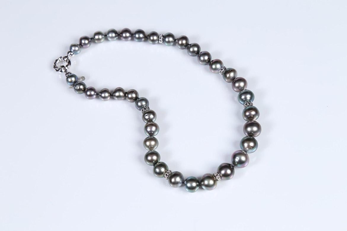 A princess necklace features 9.5 to 14.5mm black South Sea pearls enhanced by 14kt white gold, open weave spacers, and a white gold fold-over clasp.  18.5”