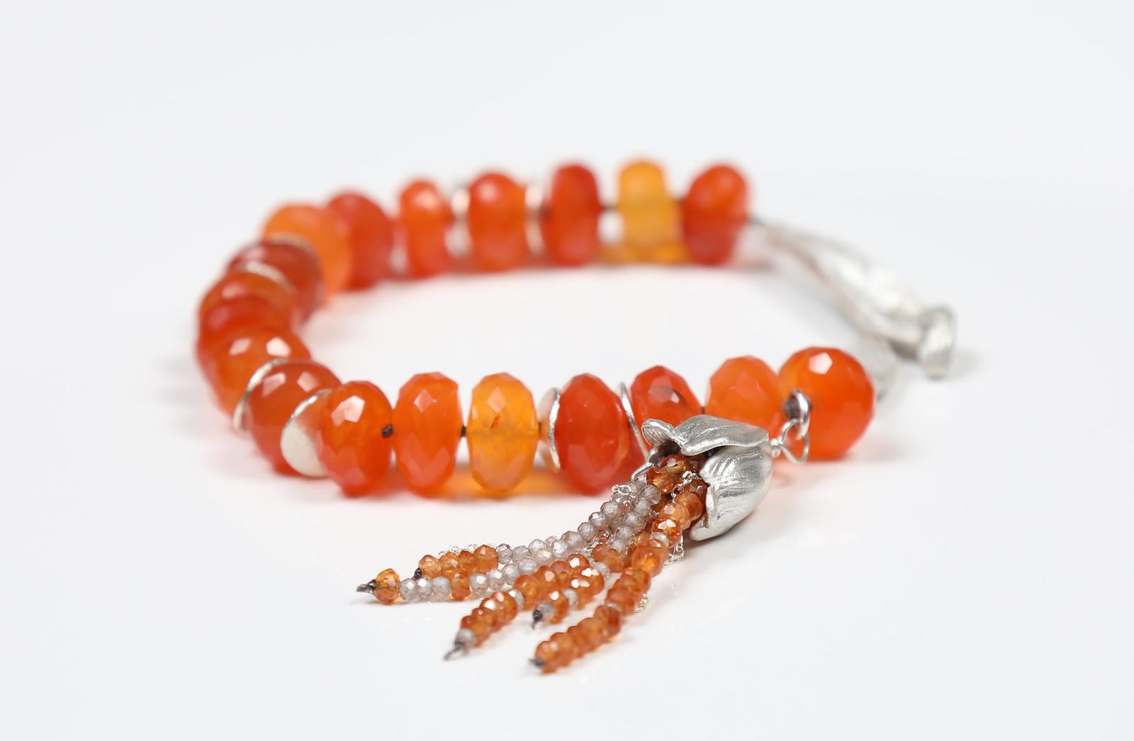 Faceted carnelian (6mm) is bounded by textured sterling spacers and closed with our artisan vanilla bean clasp.  A tassel of carnelian, rutilated quartz, and sterling chain completes the look.  7.5