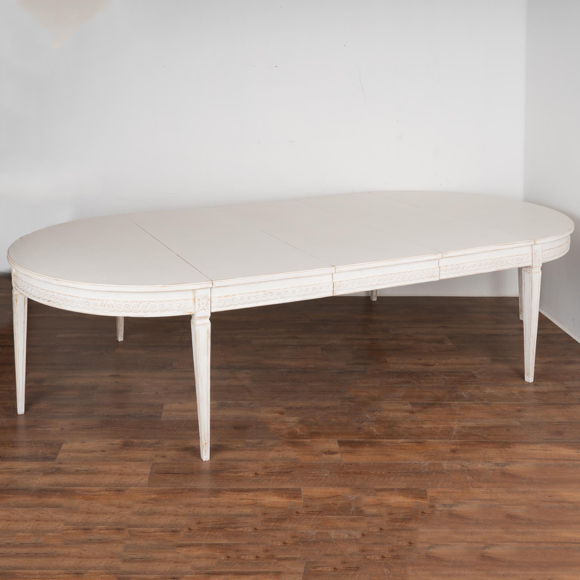 Decorative carving along the skirt and graceful lines are seen in the tapered legs of this incredible Swedish dining table, which extends to a remarkable length of just under 11 feet.
It is the newer, professionally applied white layered painted