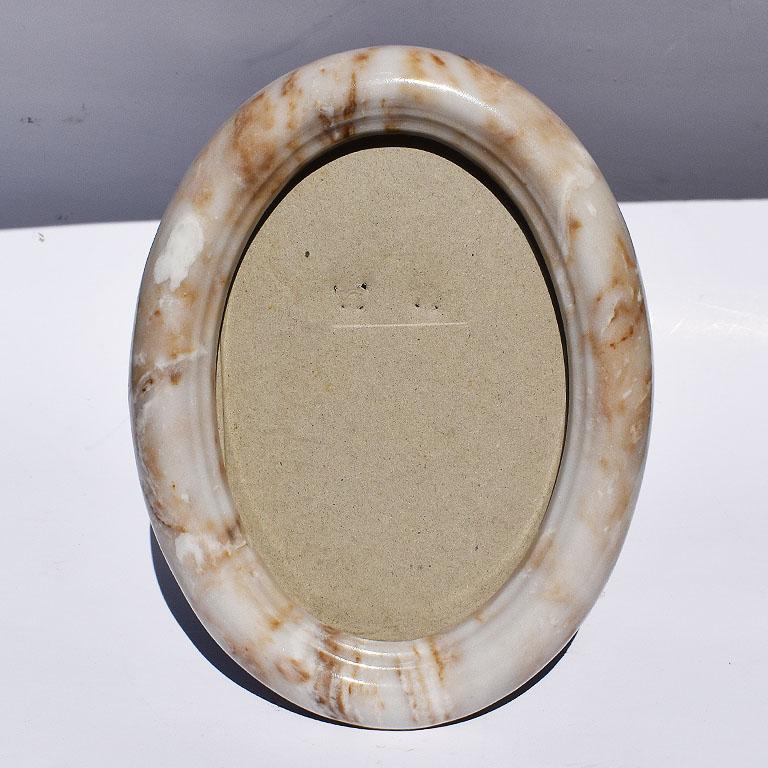 Long oval picture frame in white stone. This photo frame is perfect for a desk, bookshelf, or side table. Created from a heavy white stone with brown marbling. The back is covered in black velvet with a stand.

Specifications:
8.5