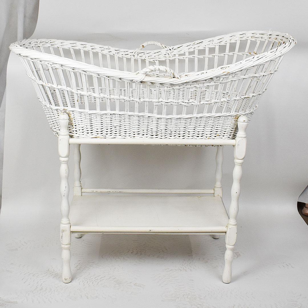 White wicker bassinet with wood storage shelf underneath. A great piece for a traditional or classical children's room, this whimsical bassinet is created from wicker and has two handles at the top. The wicker bassinet itself is removable and has