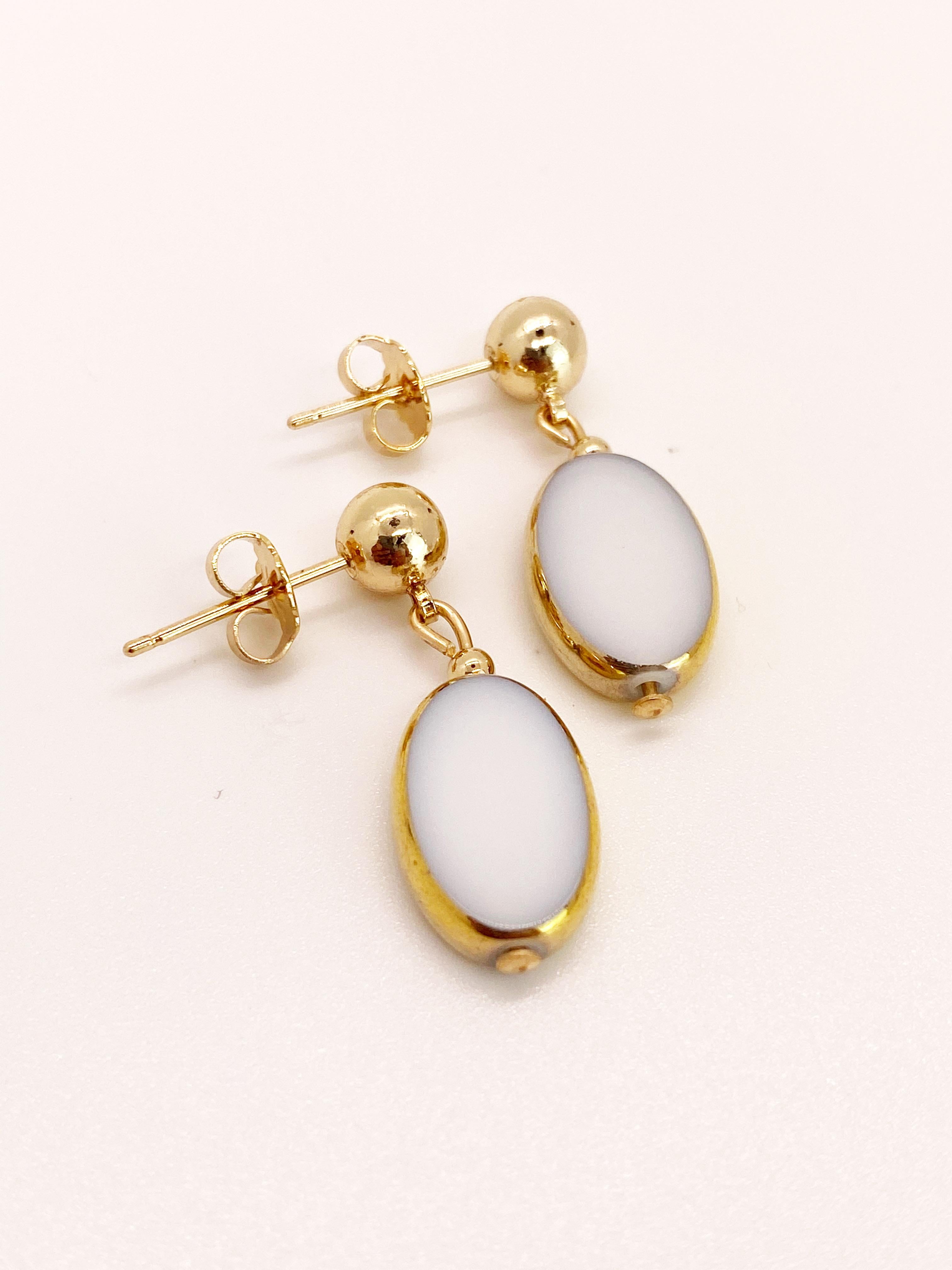 White Oval German vintage glass beads edged with 24K gold dangles on a 6mm ball 14K gold filled earring post. 

The German vintage glass beads are considered rare and collectible, circa 1920s-1960s.

*Our jewelry have maximum protection for