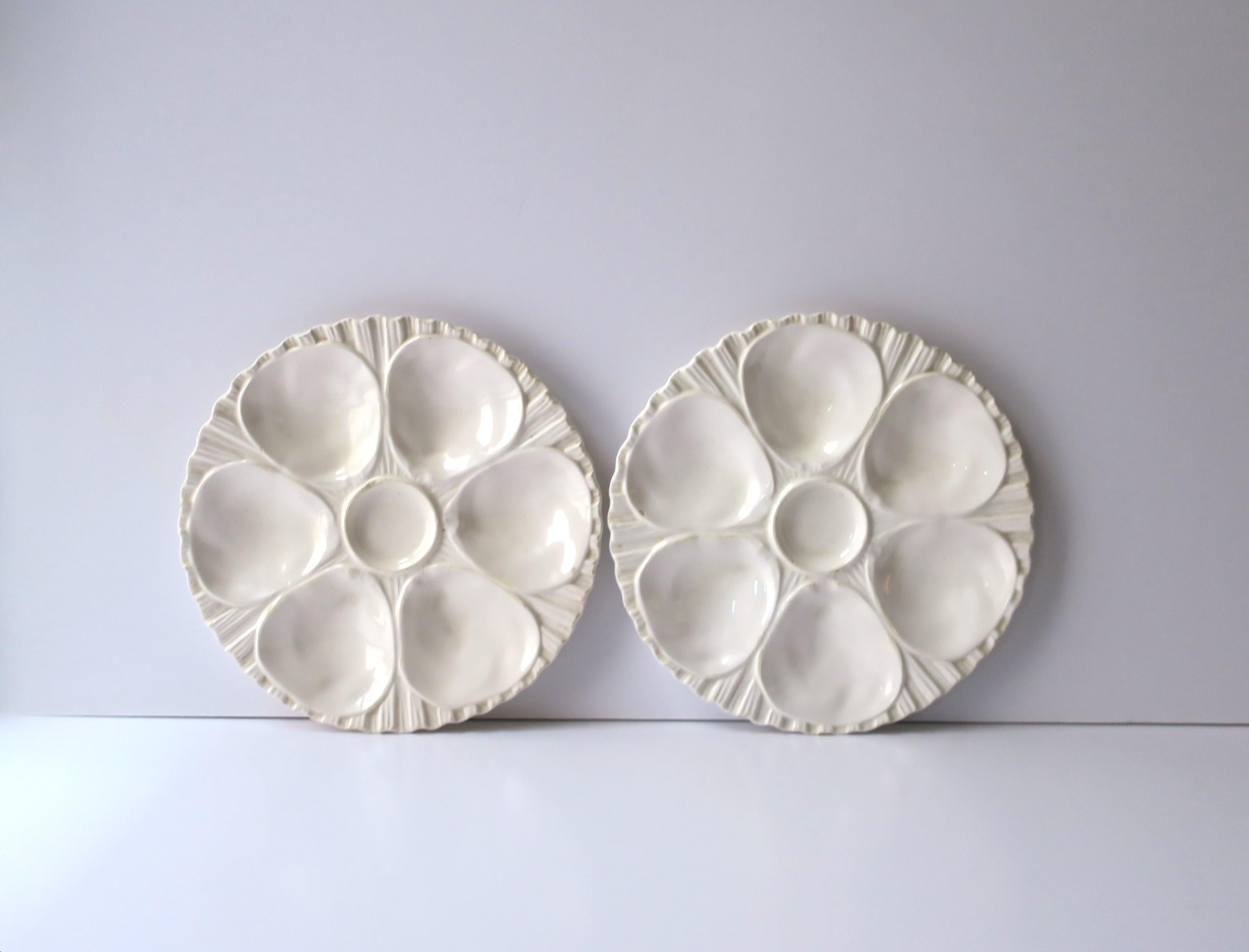 A beautiful pair of all white/off-white porcelain oyster plates, circa early to mid-20th century, Europe. Plates are white porcelain with 6 wells around, a center area for condiment, and a textured base/edge area. Great to use/serve oysters,