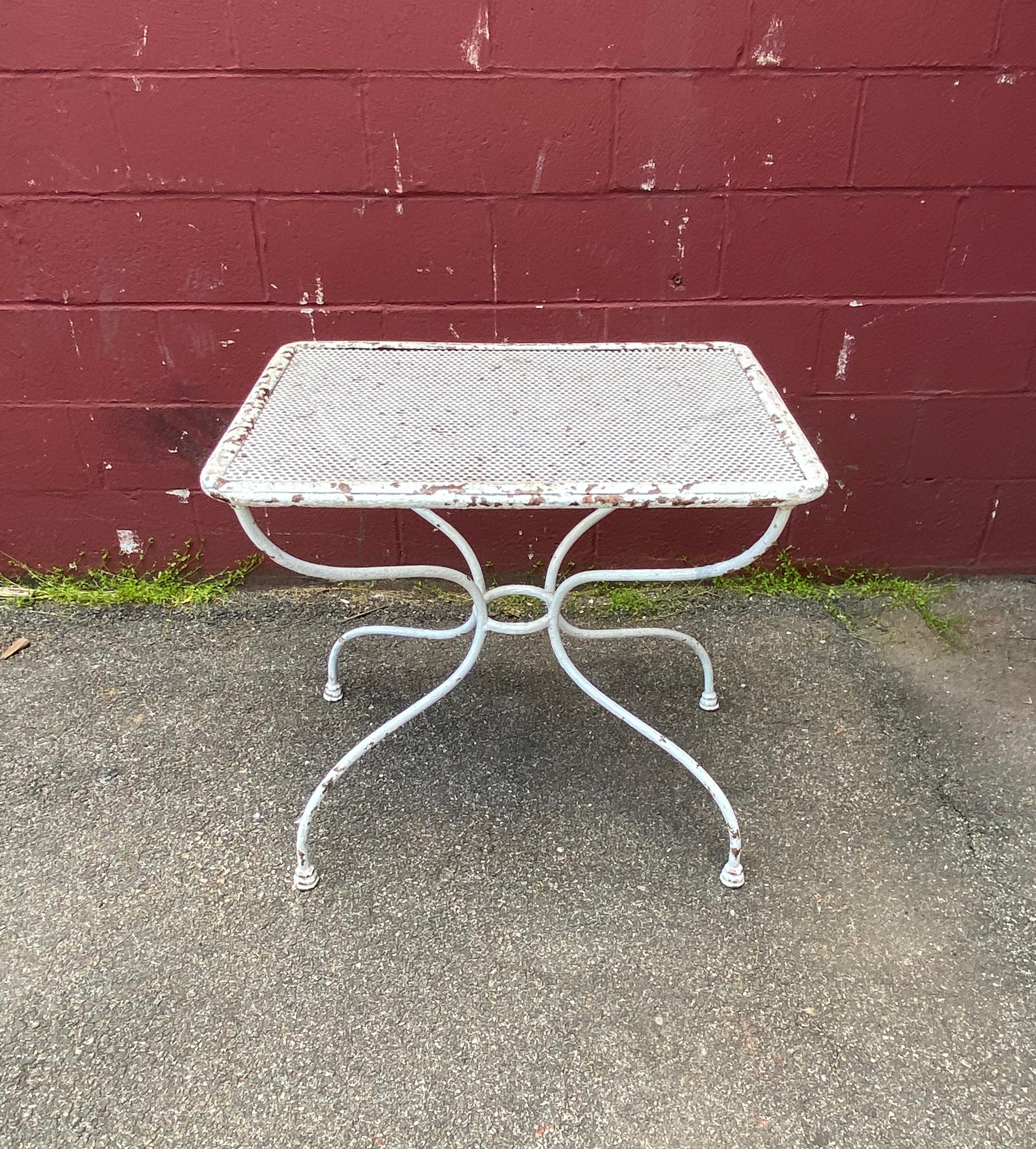This charming French garden table from the 1920s is the perfect addition to any patio, terrace, or garden. Its perforated top allows for drainage, making it ideal for outdoor use. The curved legs and center ring provide stability and a touch of
