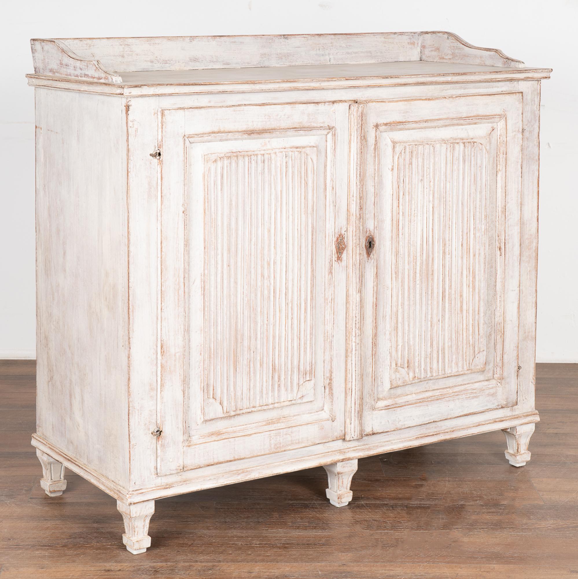 This lovely white Gustavian sideboard comes from the Swedish countryside. The simple fluted carving along the panel doors was a traditional element in Swedish furniture from this era.
The newer, professionally applied white painted finish has been