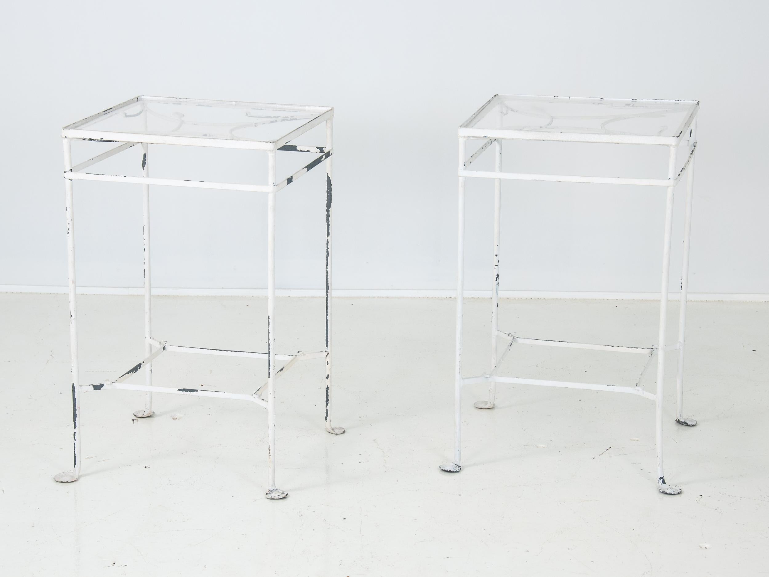 A rare pair of Salterini side tables refinished in white paint. A hard to find style, this pair currently have replacement plexi shelves for the lost glass and one leaf detail is missing. Replacement glass is recommended as the plexi has clouding.