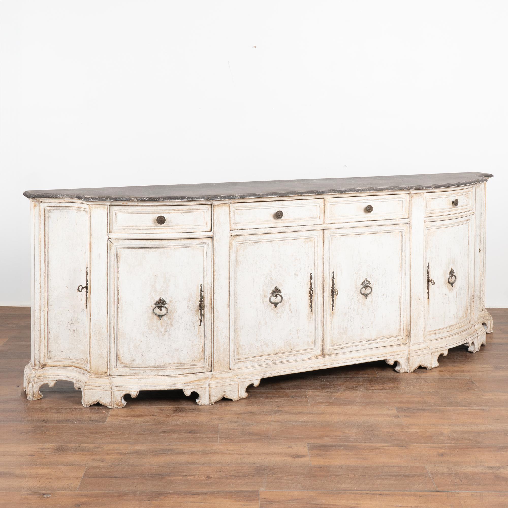 Impressive Italian painted oak sideboard with attractive concave curved end doors and decorative carved feet.
The newer professionally applied marbled and muted antique white painted finish beautifully compliments the age and grace of this beautiful