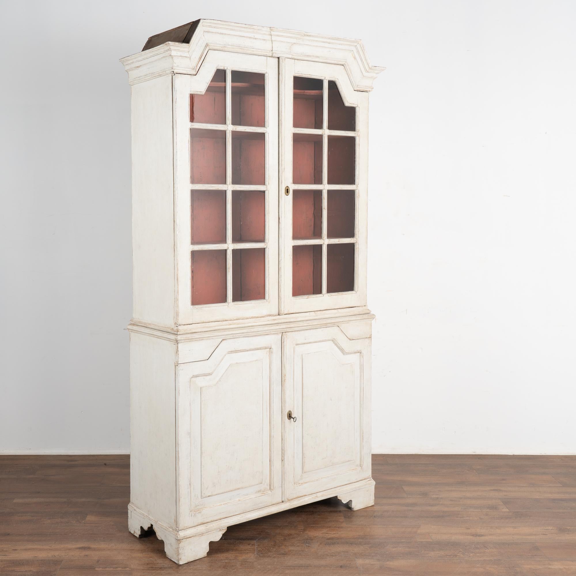 This European country pine cupboard may be used as a display cabinet or bookcase. The upper pane glass doors allow for ideal display of any collection held within.
The newer professionally applied white painted finish is complimented by the