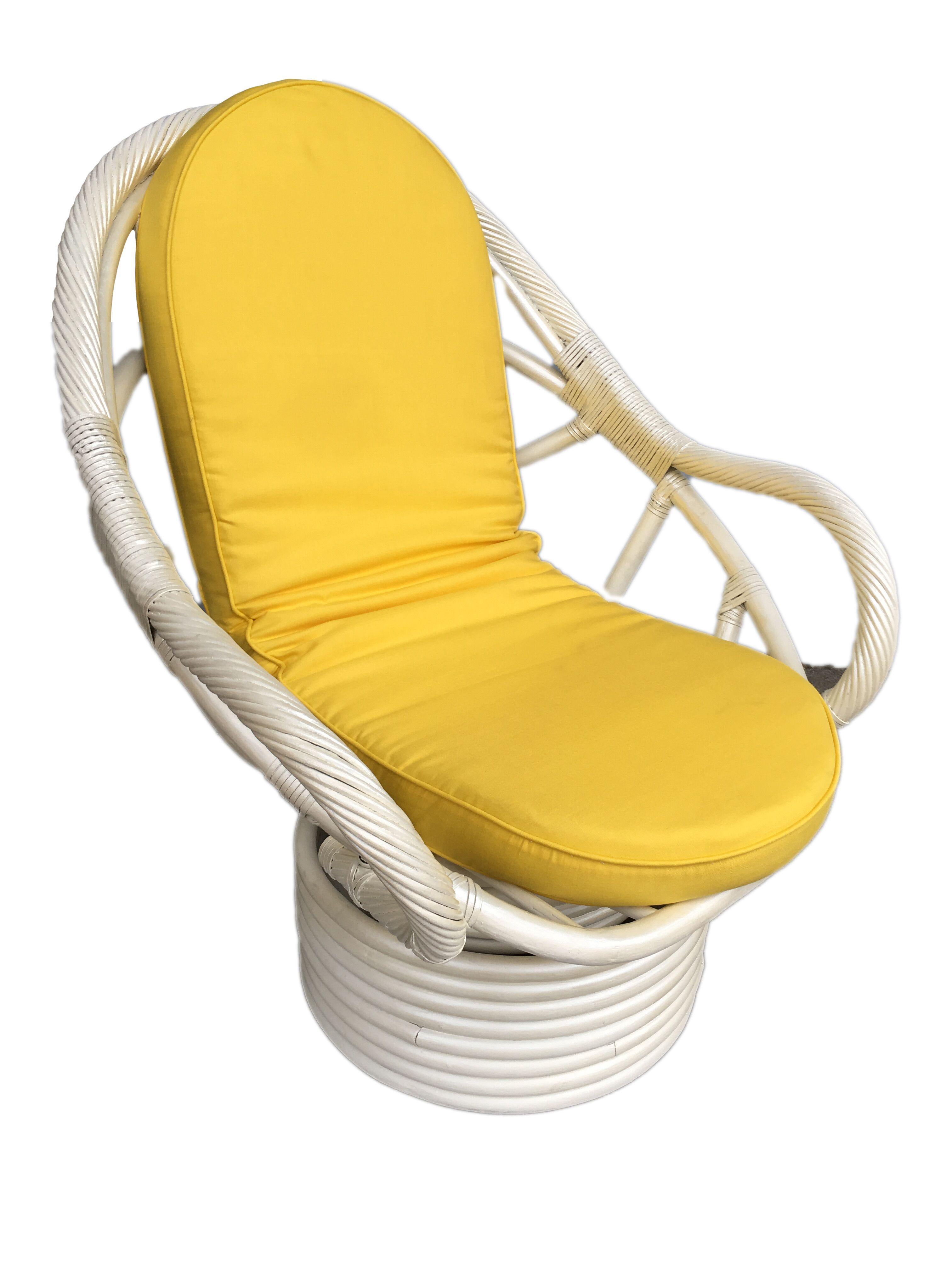 White painted rattan bucket lounge chair with swivel base featuring a ball-like shape with stick rattan wrapped arms. Circa 1970 Cushions are C.O.M. Restored to new for you. Restored to new for you. All rattan, bamboo and wicker furniture has been