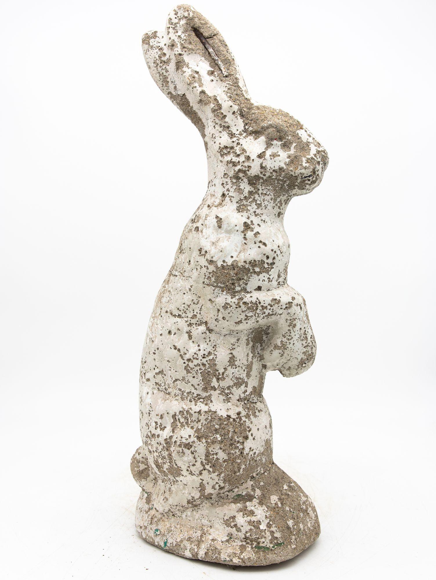 A charming 20th century French garden ornament depicting a seated rabbit with its front feet raised. Crafted from reconstituted stone, this piece features a white-painted body, elegantly shaped ears, and charming folded-feet that bring it to life.