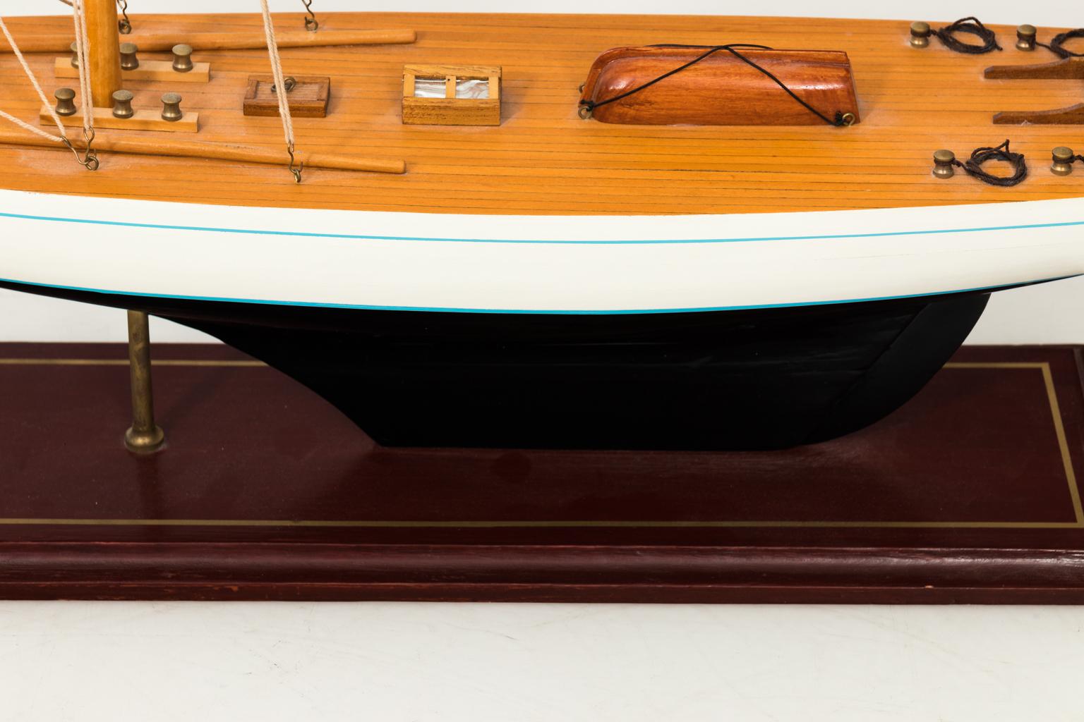 Contemporary white painted model of a sailing boat on a wood base.
 