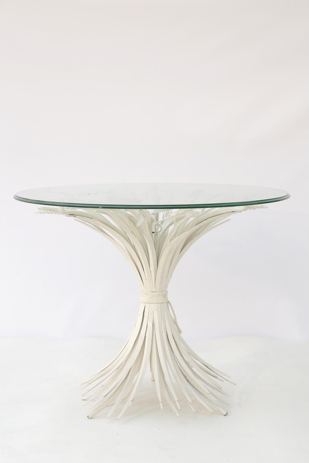 Accent table, of painted metal, in the form of a bundle of wheat, tied with rope at its middle, with round glass top. 

This classic, Hollywood Regency, the design was made popular when both Coco Chanel and Yves Saint Laurent utilized them in