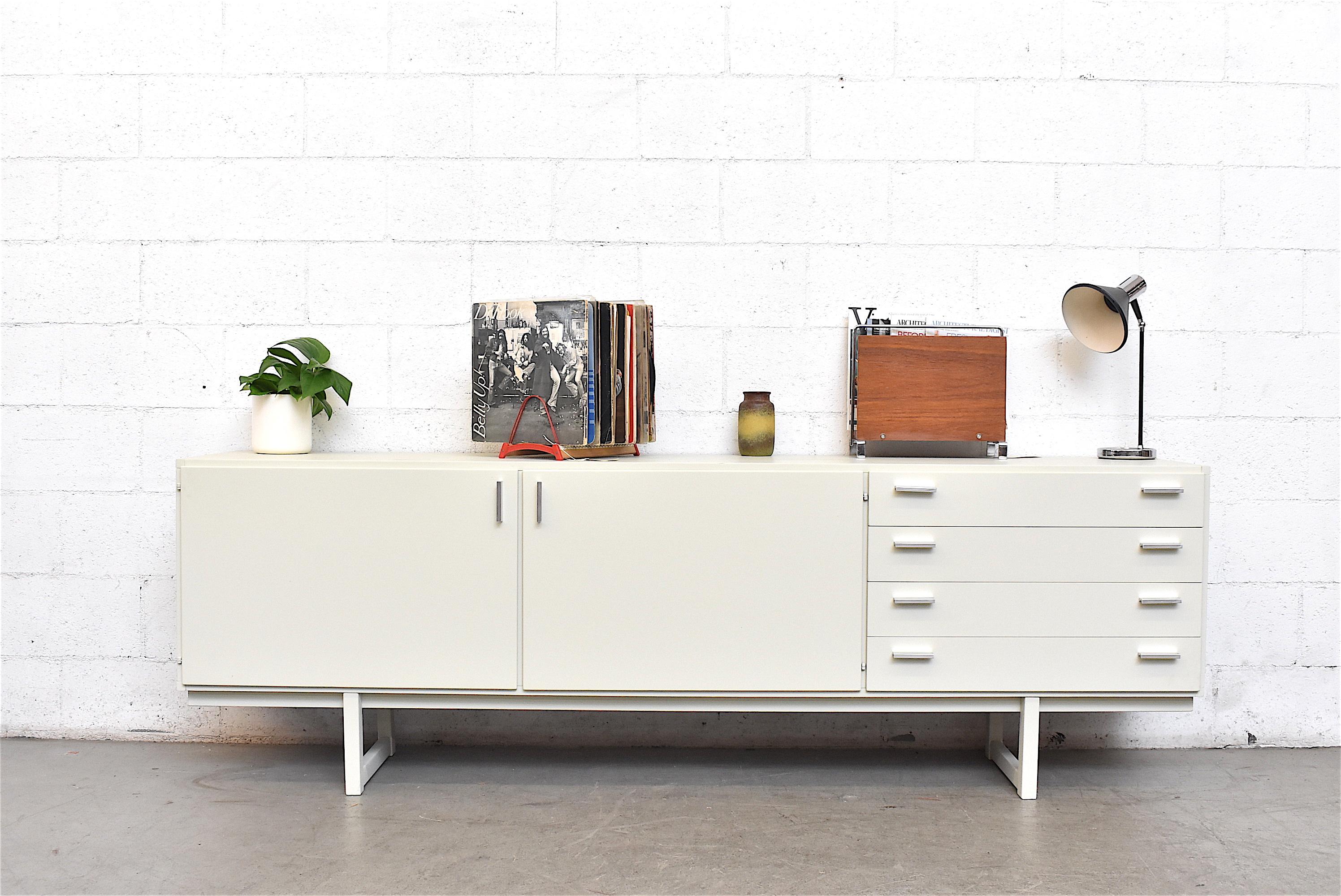 Large midcentury white lacquered and lightly refinished credenza with signature curved interior drawers and double doors all with cast aluminium hand pulls. In good original condition.