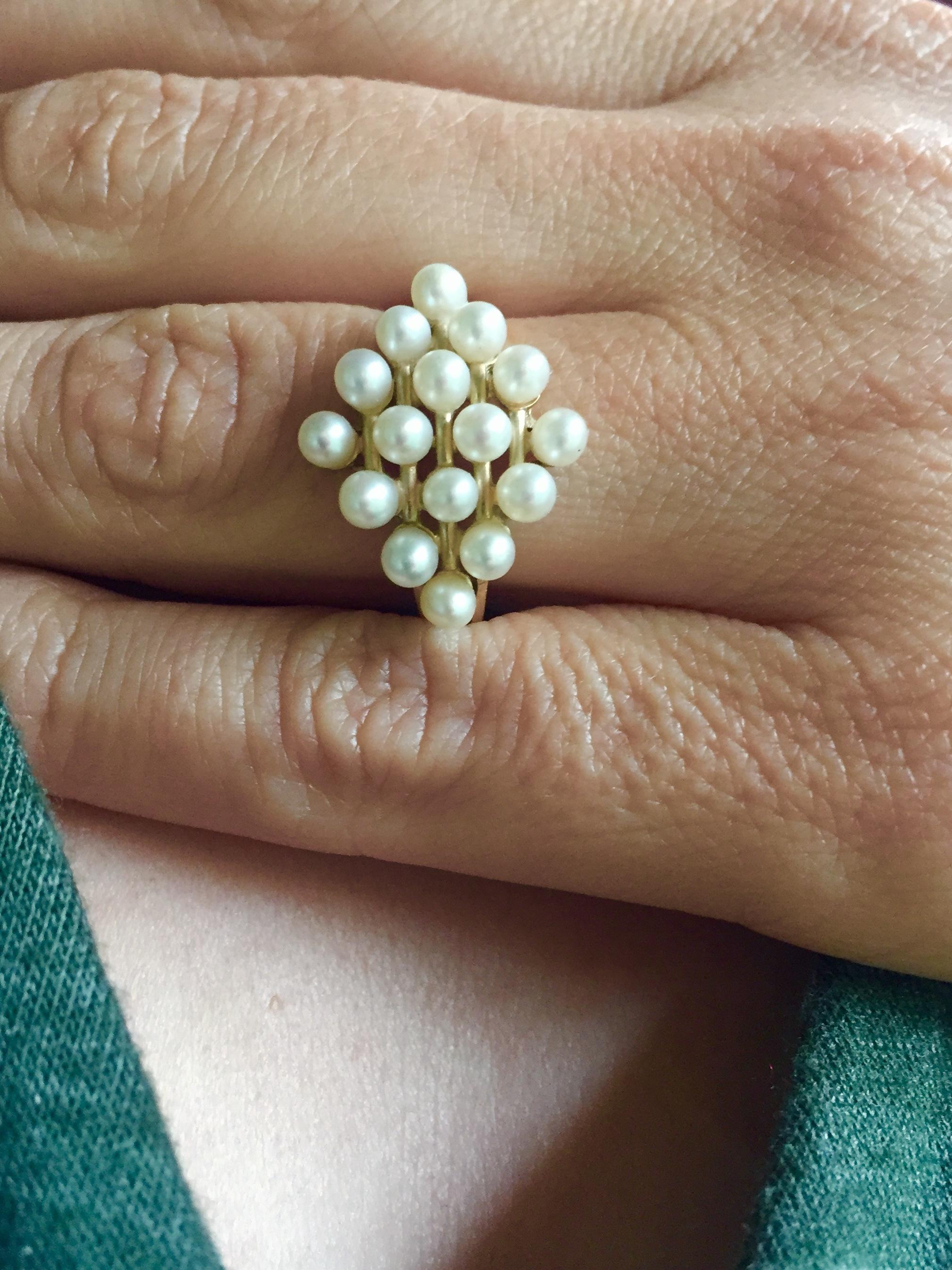 This white pearl and 14k yellow gold ring is size 8. With a diamond-shaped design consisting of glowing round white pearls, 14k yellow gold setting, and ring, this ring is an elegant choice. It is classic with white pearls and yellow gold, yet
