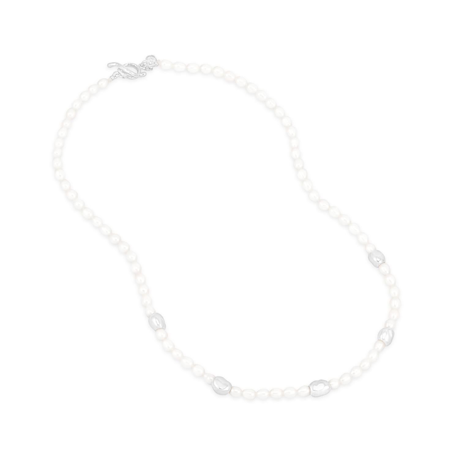 Enhebrado a mano en nuestro estudio londinense, este lustroso collar de perlas se deslizará a la perfección en tu colección de básicos de estilo. La moderna mezcla de perlas blancas ovaladas de agua dulce y 5 brillantes cuentas de guijarros