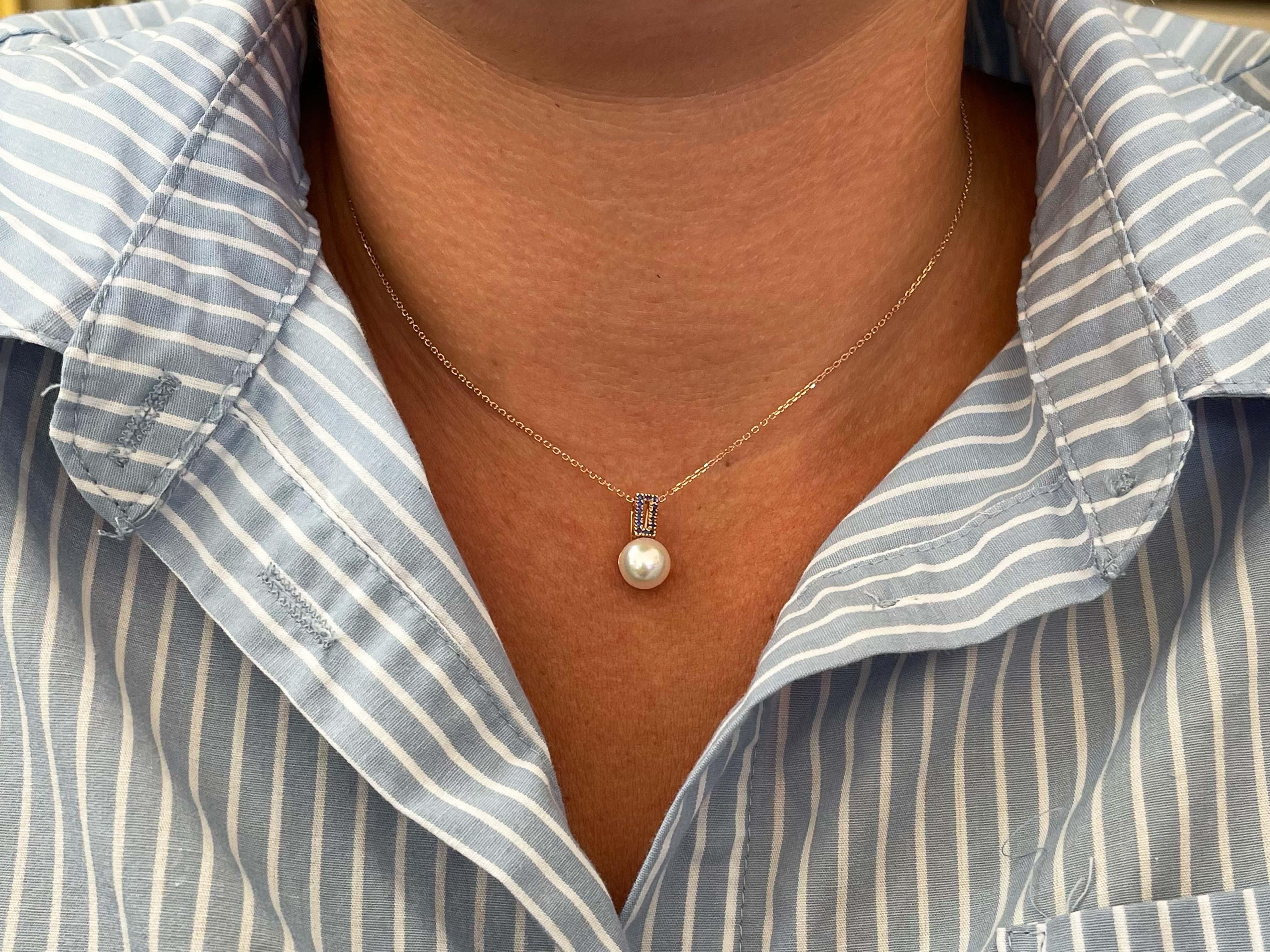 White Pearl and Sapphire Pendant with Chain in 14k Rose Gold. The pendant features a white akoya pearl, 8.4 mm in diameter and has 14 deep blue, bead set, round sapphires in a rectangle shape above the pearl. The pendant comes on a 16