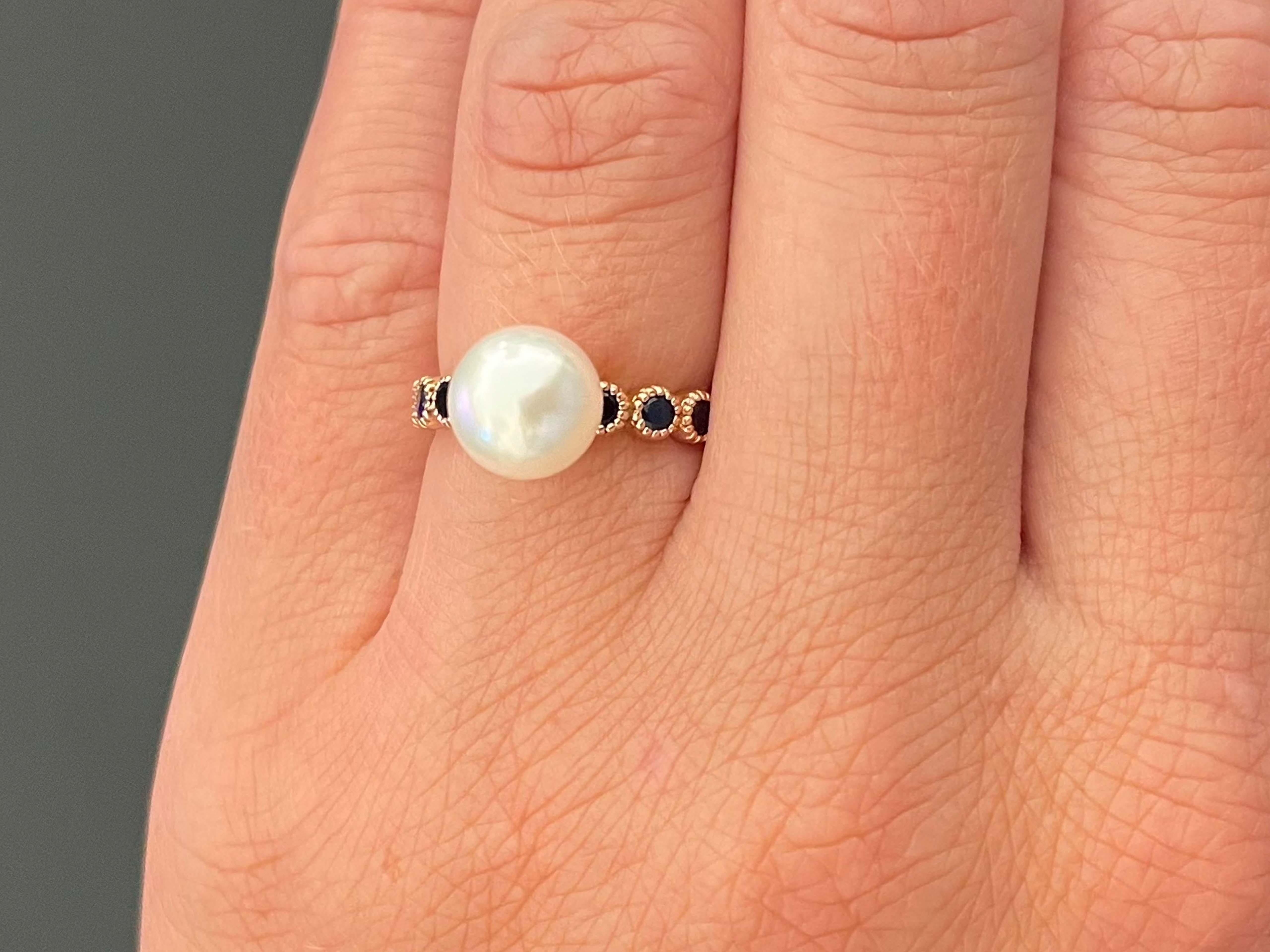 White Pearl & Sapphire Ring in 14k Rose Gold. The center of this beautiful ring features a white akoya pearl, 8.4 mm in diameter and the band is bezel set with 8 deep blue round sapphires. The ring is size 5.75 and can be easily re-sized for a small