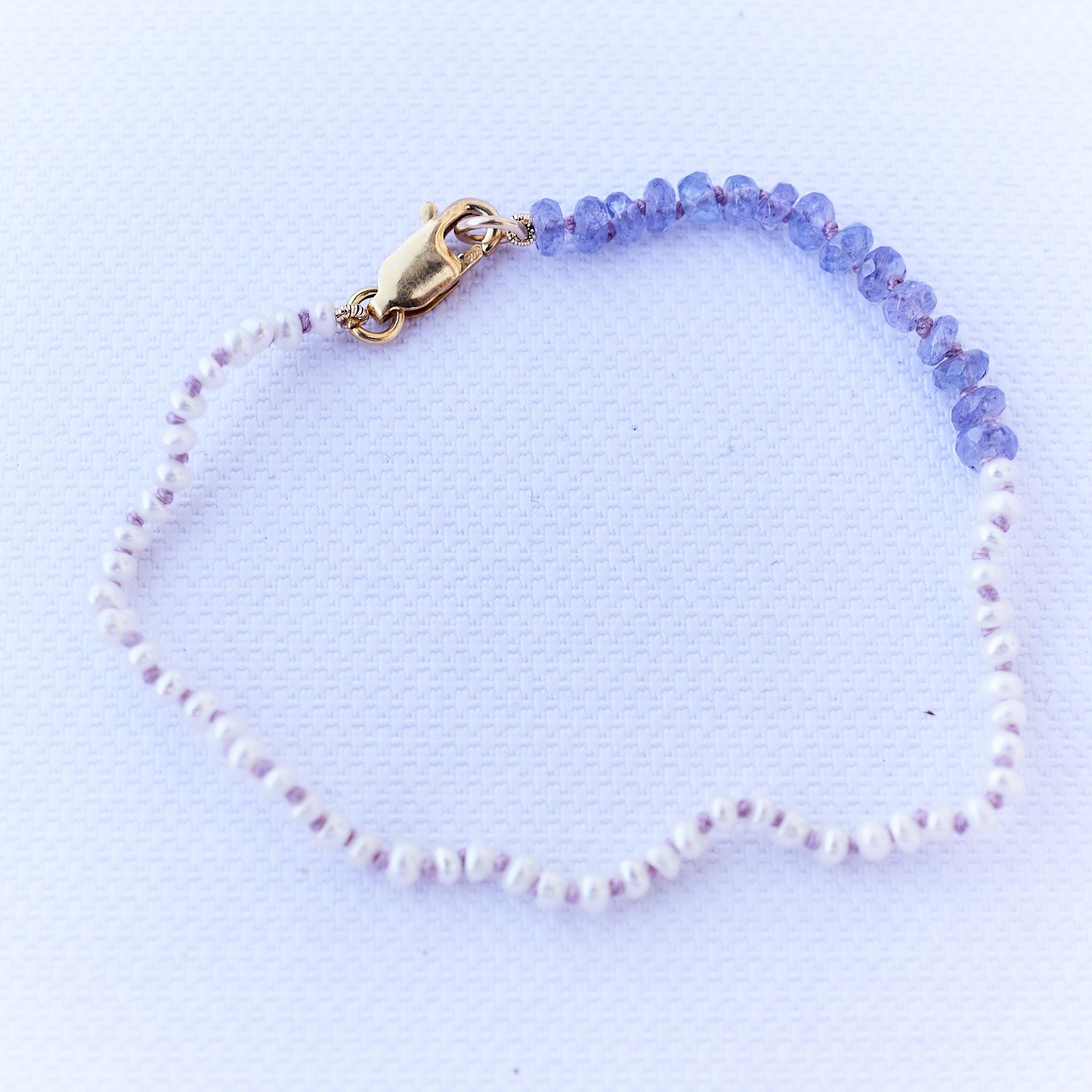 White Pearl Tanzanite Beaded Bracelet 
Lilac Silk Thread 
Designer: J Dauphin
Metal: Gold Filled Clasp

J Dauphin jewelry is hand made in Los Angeles and was created by designer Johanna Dauphin. Most of the jewelry is unique or created in small