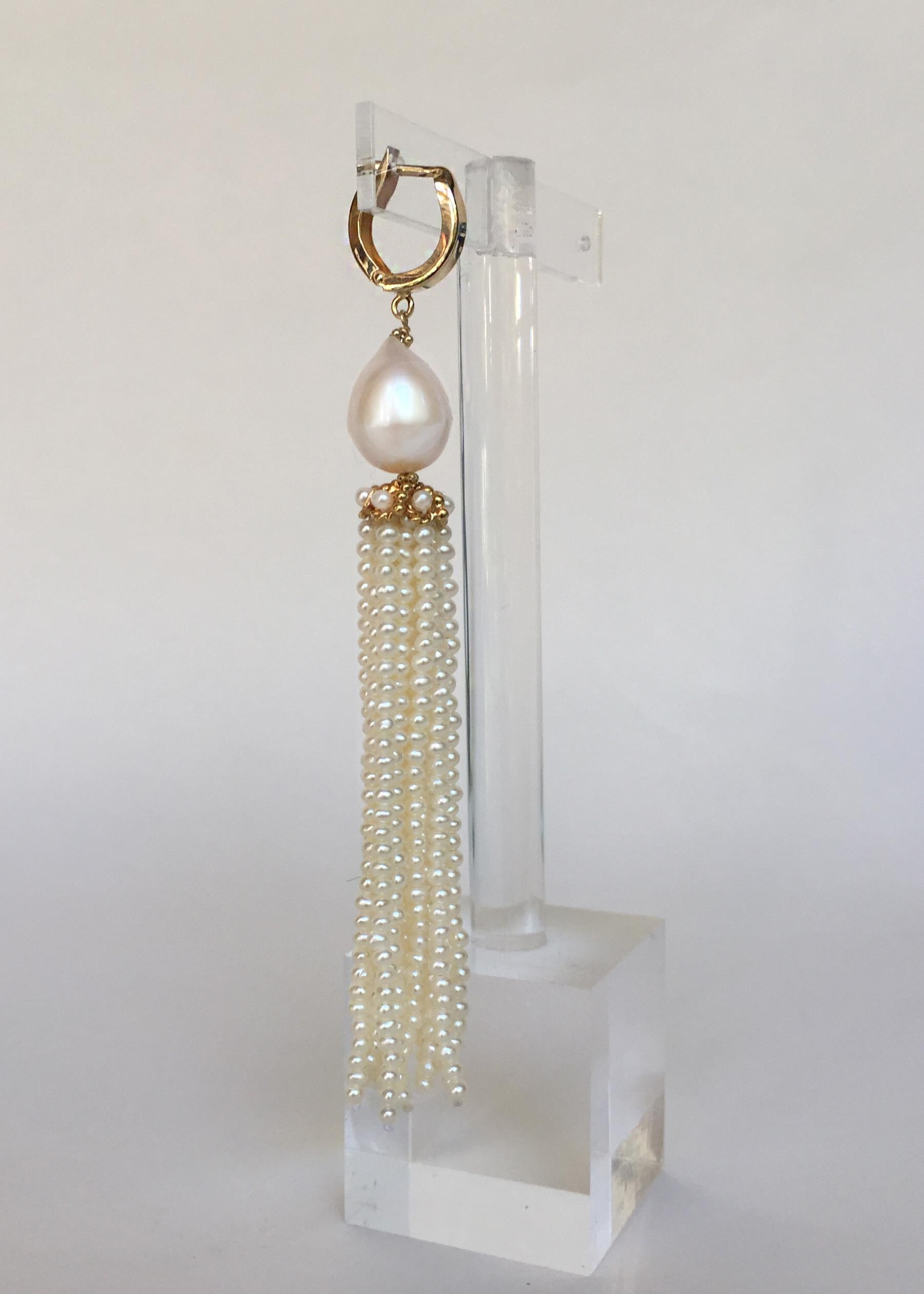These glowing white pearl tassel earrings are highlighted with  detailed 14k yellow gold cups and lever backs. The tassel strands are made with small 1mm cultured round pearls that glisten with the movement of the tassel. Woven through the 14k