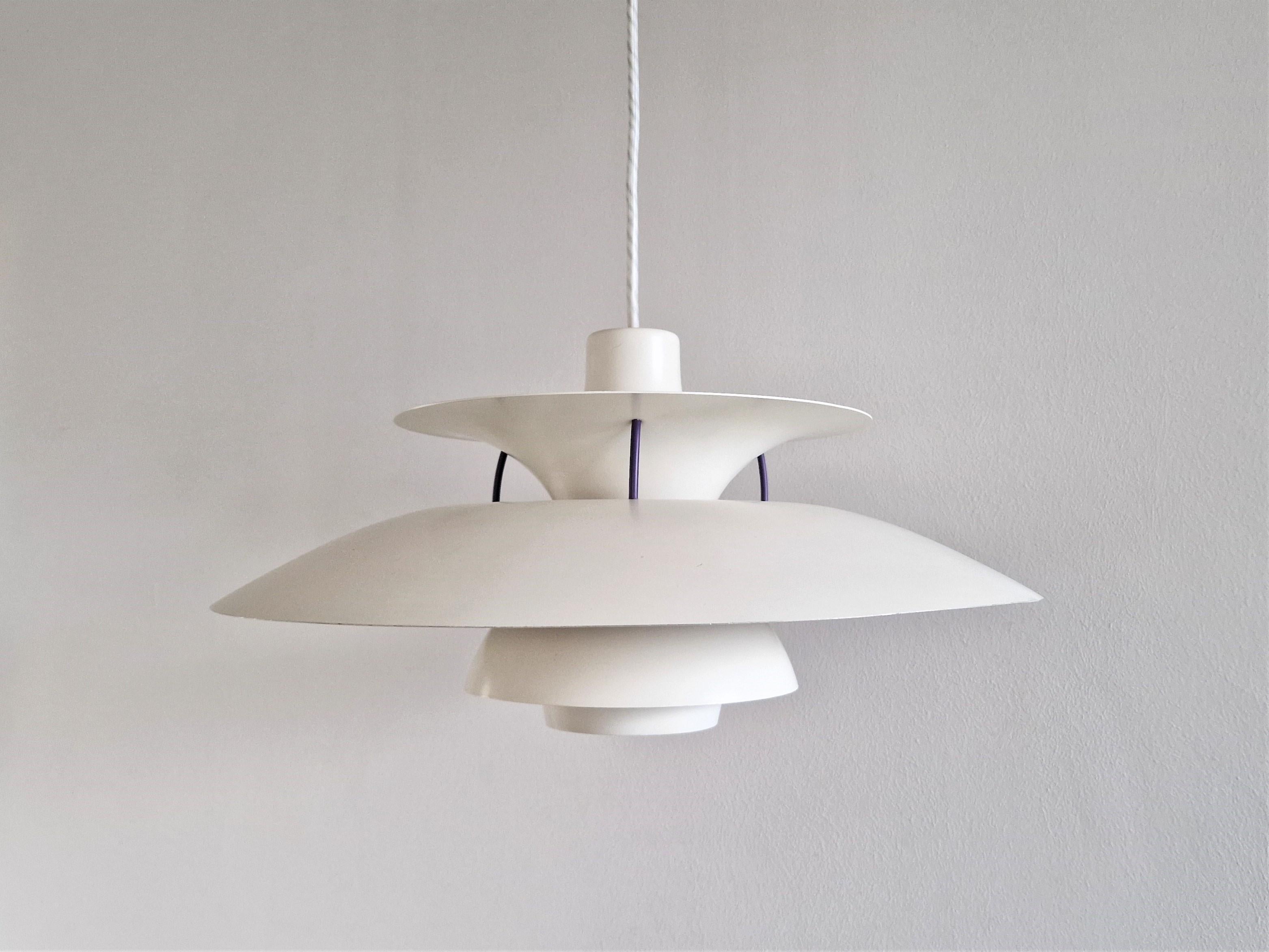 This timeless model PH5 pendant lamp was designed by Poul Henningsen for Louis Poulsen in 1956. The lamp has a white shade with blue and red details and blue connecting elements. It is in a very good condition with signs of age and use and it is