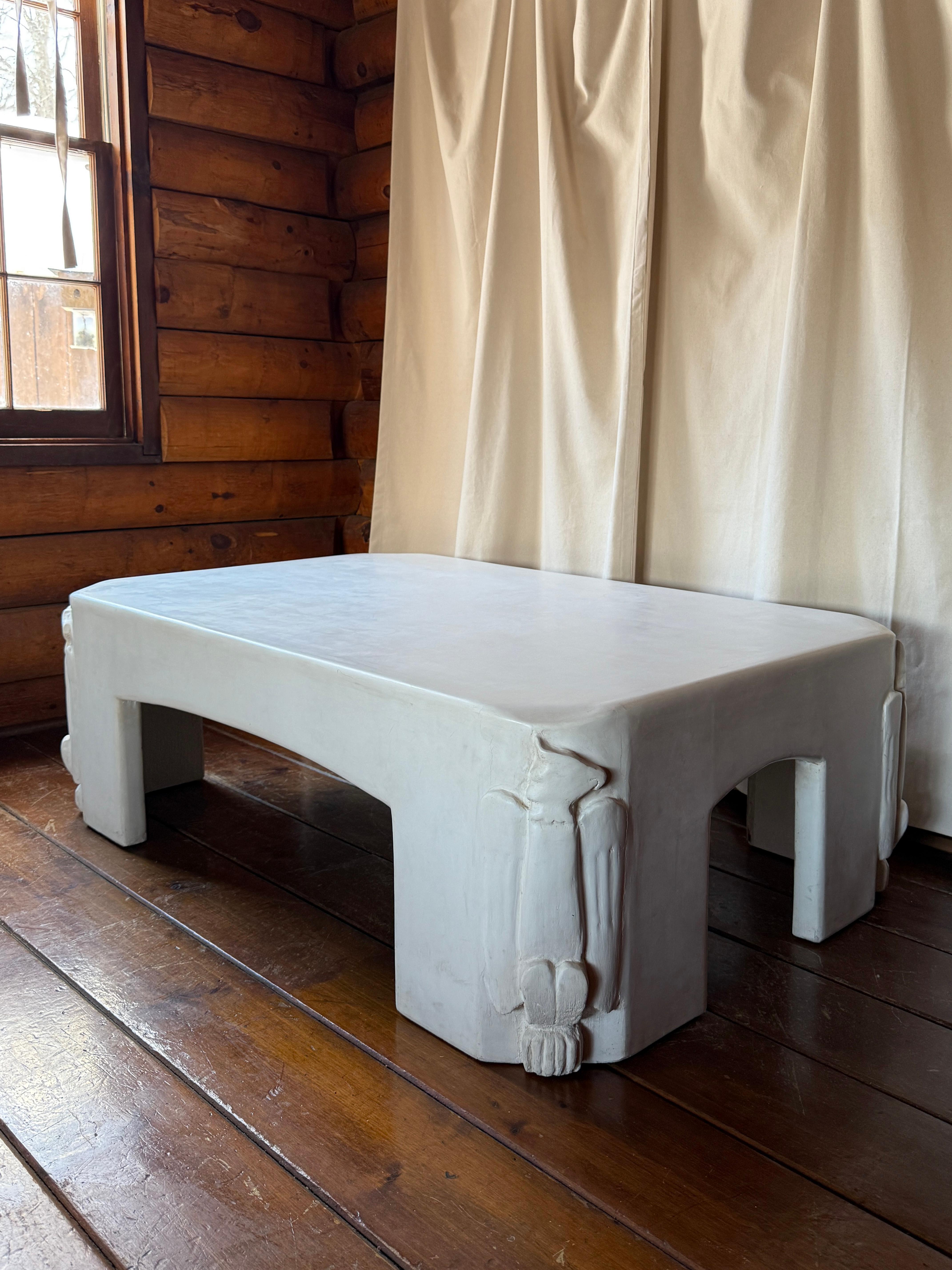 Table basse en plâtre blanc avec détails déco 
d. 2025
 
Table basse en plâtre blanc avec des détails de style déco représentant des aigles à chaque coin. L'artiste n'est pas connu mais il est clairement fait à la main avec amour. La table a été