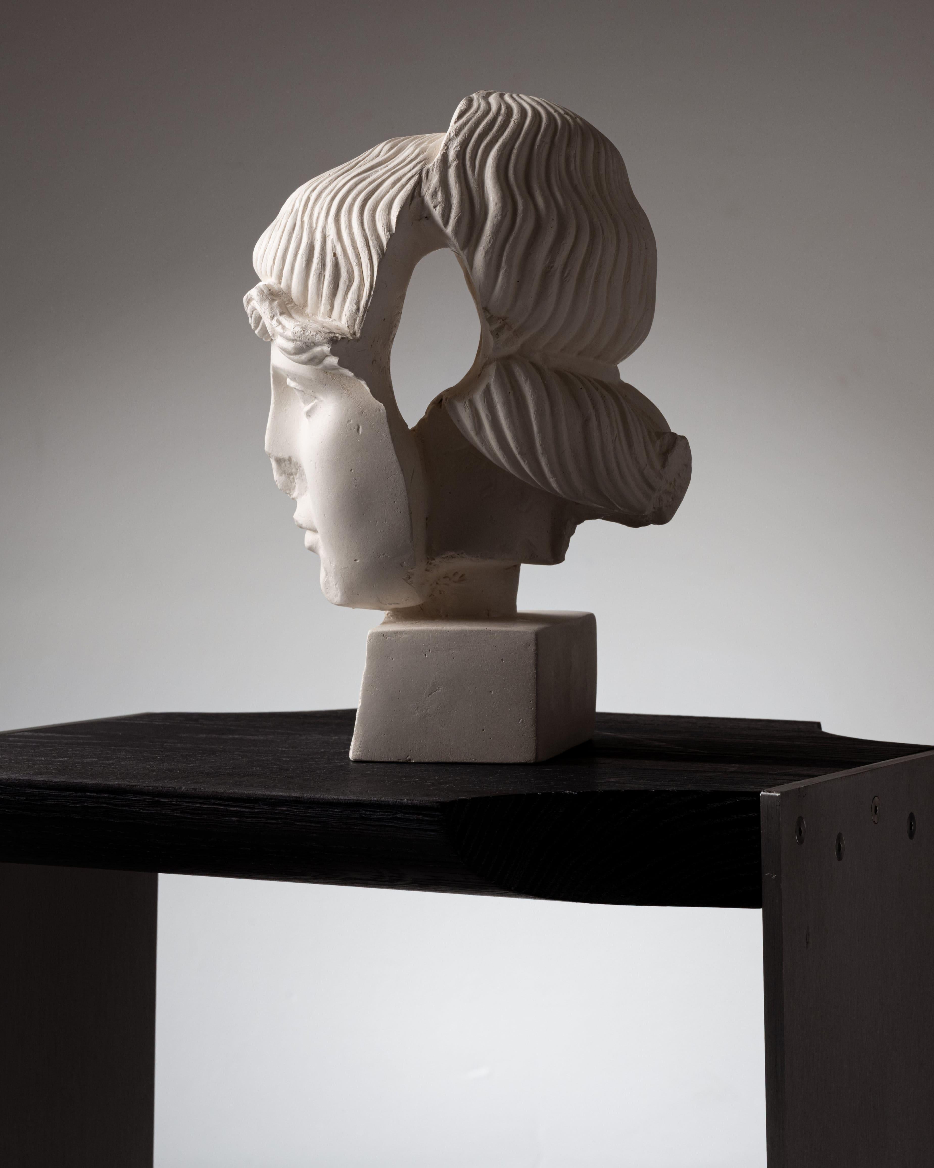 White plaster sculpture “FRAGMENT #9” by artist Marina Mankarios.
Each piece is unique and made of plaster. Marina Mankarios stages Greco-Roman models in a fragmented or distorted way, aiming to give them new expressiveness. She explores the
