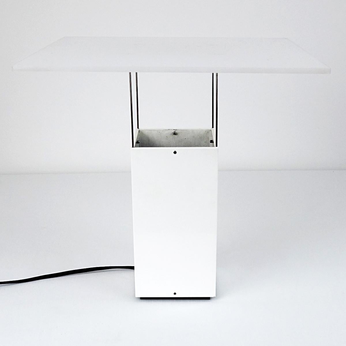 This elegant table lamp has a solid base above which a panel seems to float.
The panel, like the base made of white plexiglass, is carried by four very thin metal sticks.
The lamp is attributed to Dutch designer Benno Premsela for two reasons. The