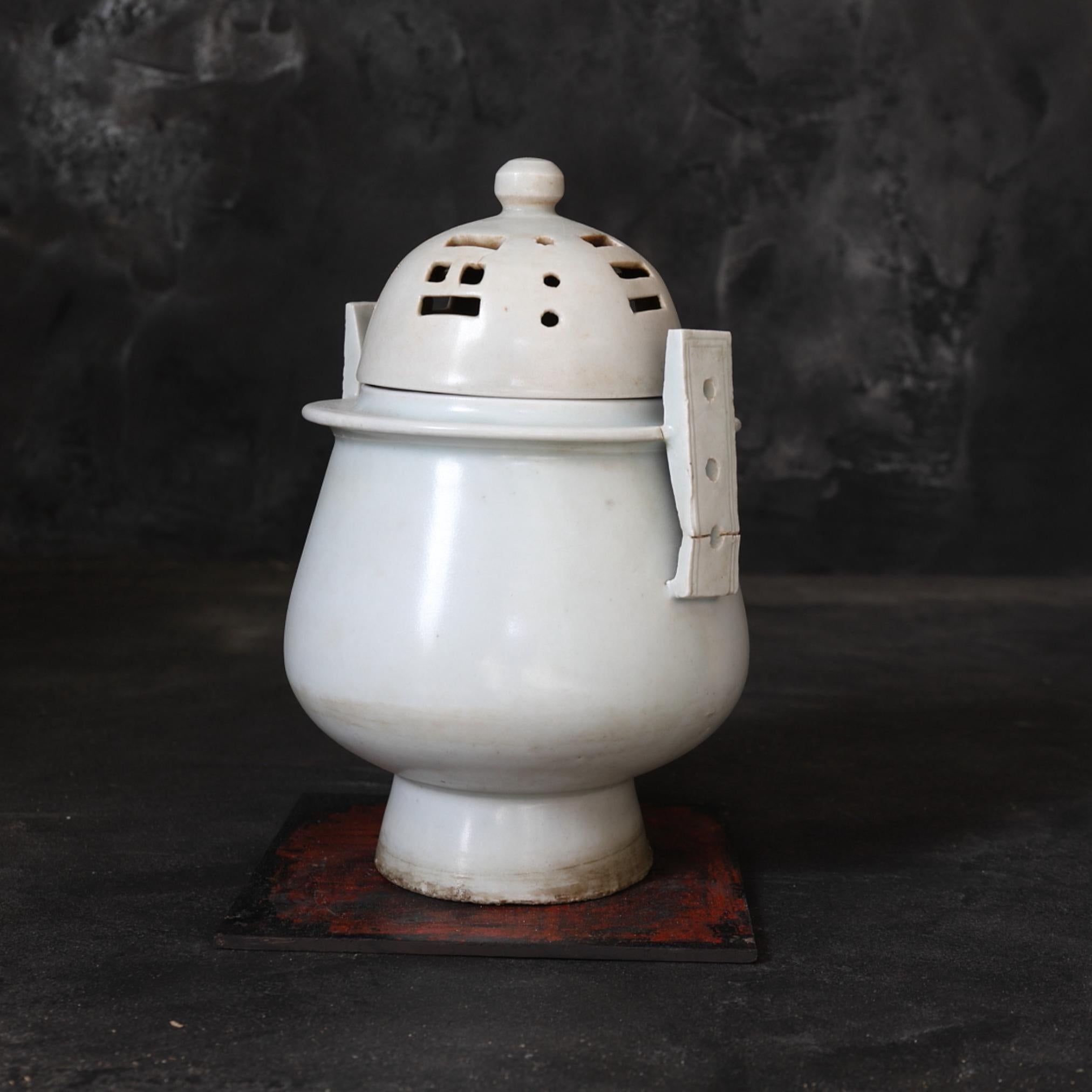 This incense burner presents the characteristics of a typical Yi Dynasty Joseon Dynasty incense burner with a body that rises smoothly from the base, openworked ears and a semi-circular lid.

The white porcelain is baked well, and the rustic white