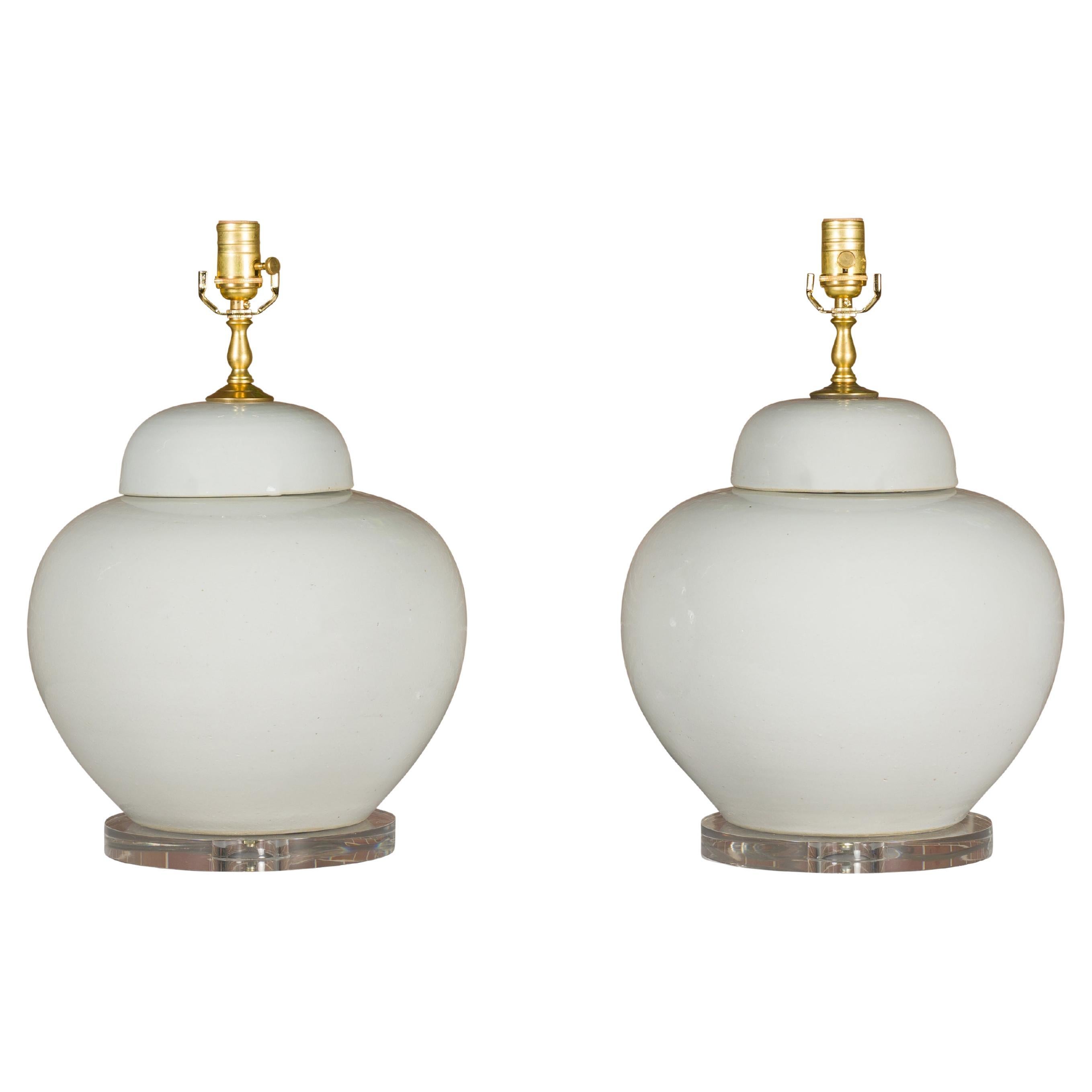 White Porcelain Lidded Urns Made into Wired Table Lamps on Lucite Bases, a Pair For Sale