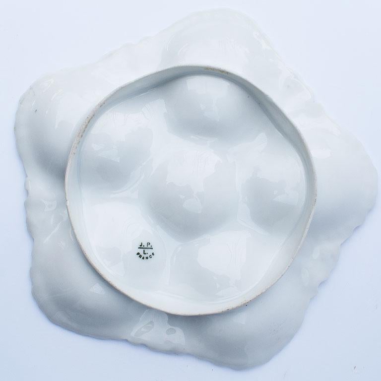 5 well white porcelain oyster plate. Beautiful scalloped edge octagonal dish with five wells for oyster shells and a center well for butter. 

Signed at the bottom: Jean Pouyat Limoges
J.P.
L.
France
1890-1932

Mesures: 8.5