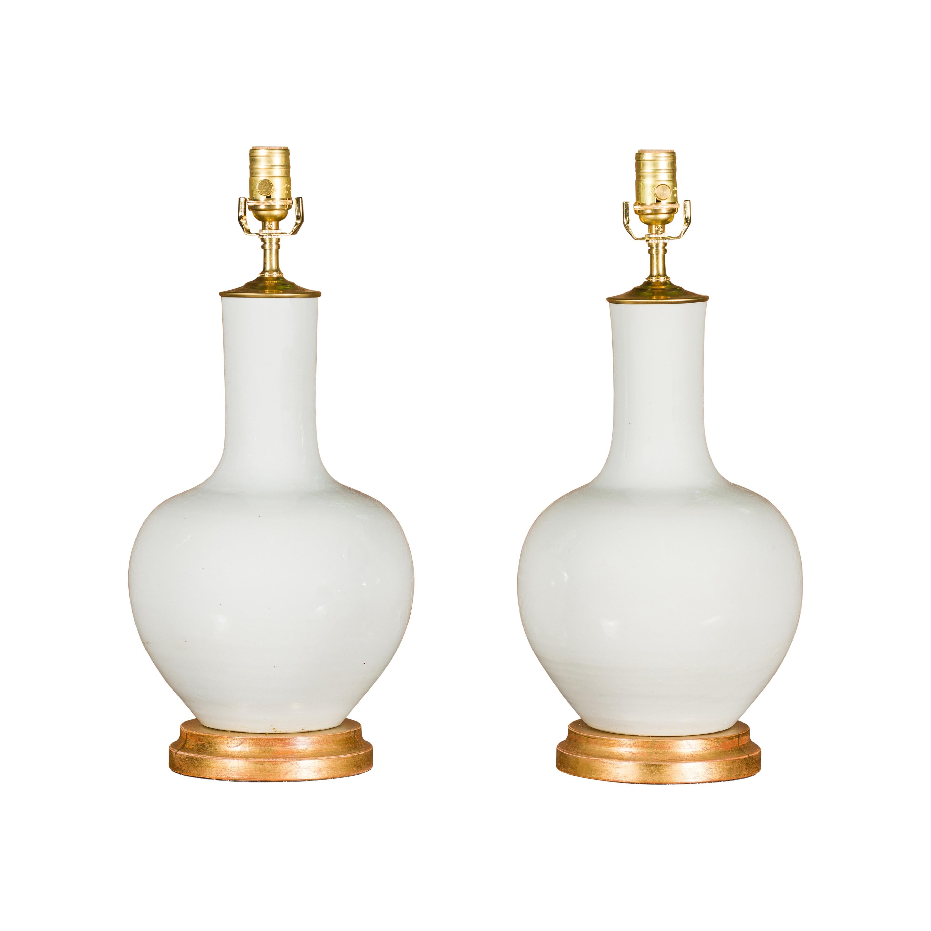 Paire de vases en porcelaine blanche transformés en lampes de table câblées sur bases en bois doré en vente 8