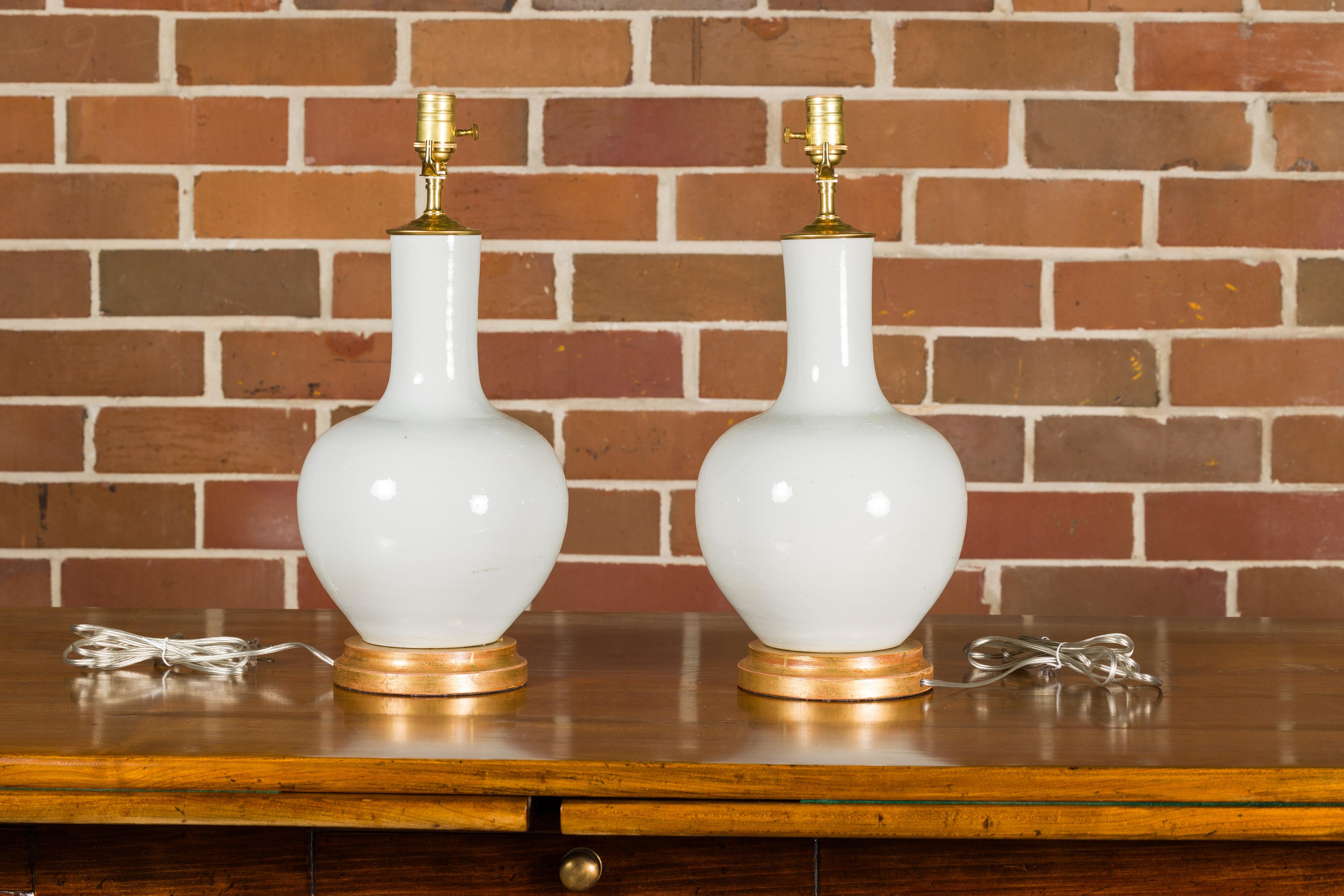 Asiatique Paire de vases en porcelaine blanche transformés en lampes de table câblées sur bases en bois doré en vente
