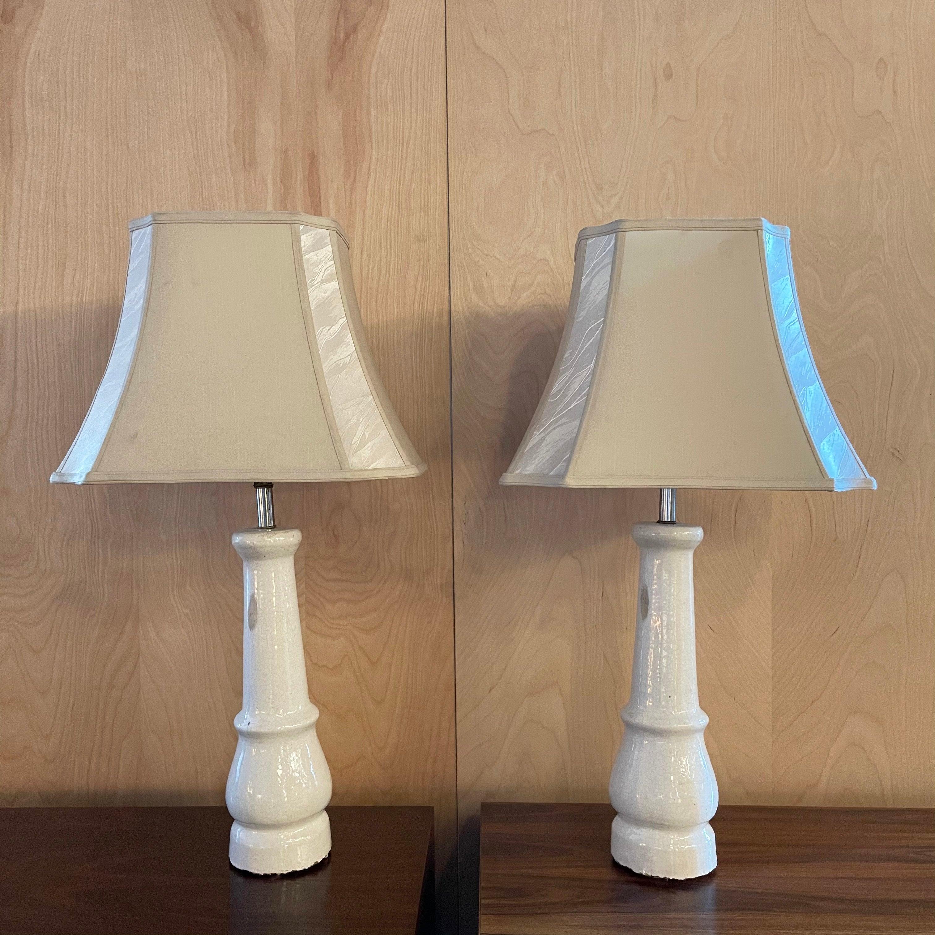 Pair of antique table lamps are created from early 20th century, patinated porcelain legs with brushed nickel necks and brass sockets, harps and finials. The lamps are newly wired with gray cloth cord to accept up to a 75 watt bulb each. The