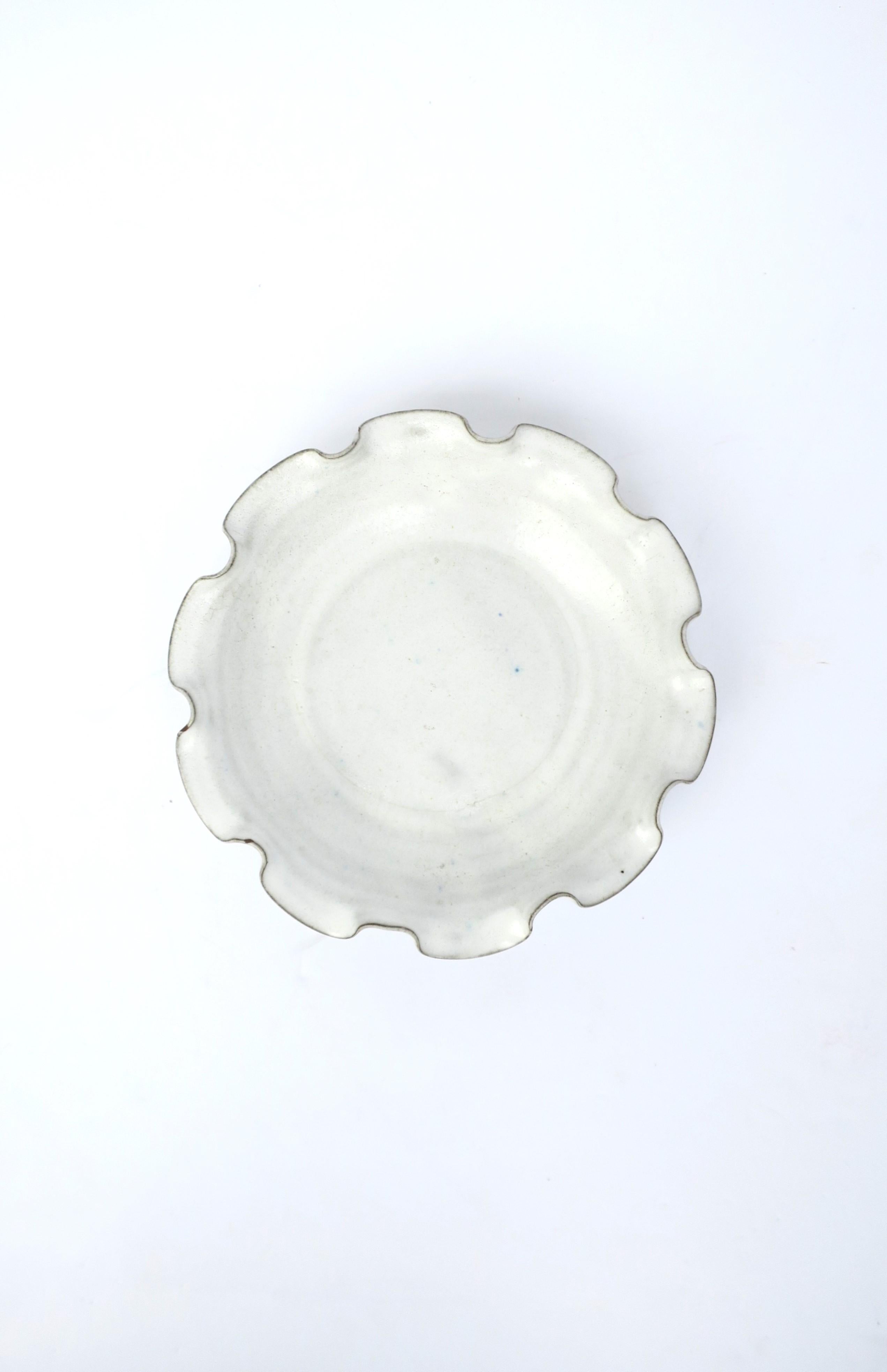 A beautiful white pottery bowl with ruffled edge. Great as a standalone piece, as a catch-all, or serving bowl. Dimensions: 8.75