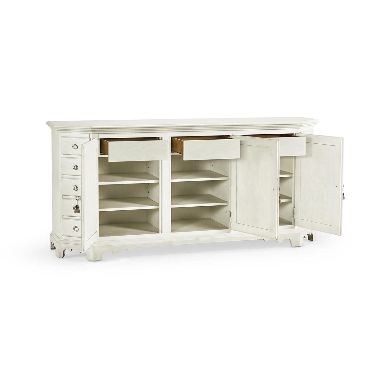 The chalk white painted sideboard has a unique canted corner design with thirteen hand-crafted drawers. Behind classically sculpted doors finished in nordic wheat, three interior drawers feature removable felt-lined silverware trays.

With