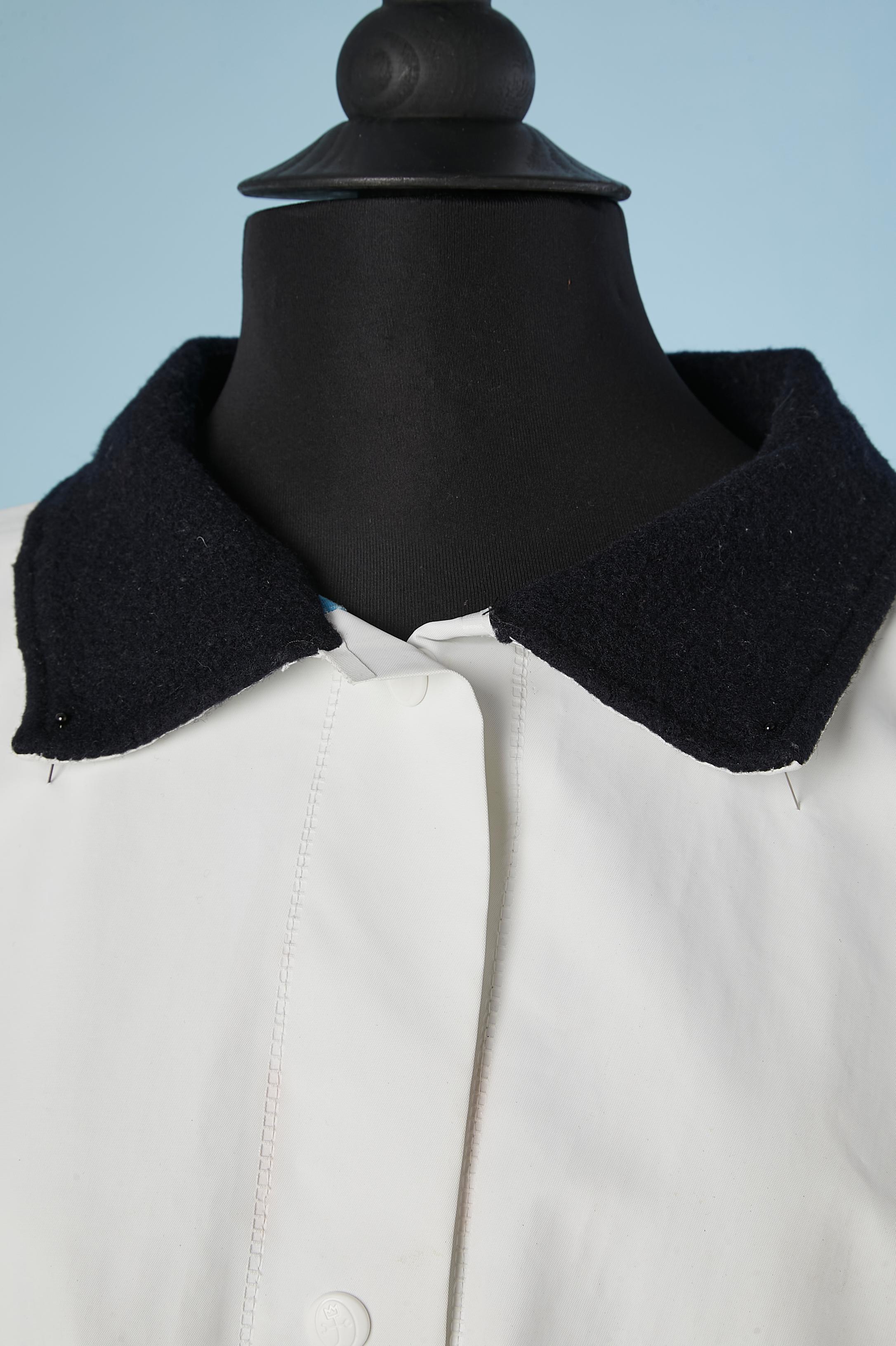 Imperméable en PVC blanc avec col en laine et doublure en coton imprimé. Bouton-pression de la marque, poches zippées. 
TAILLE L