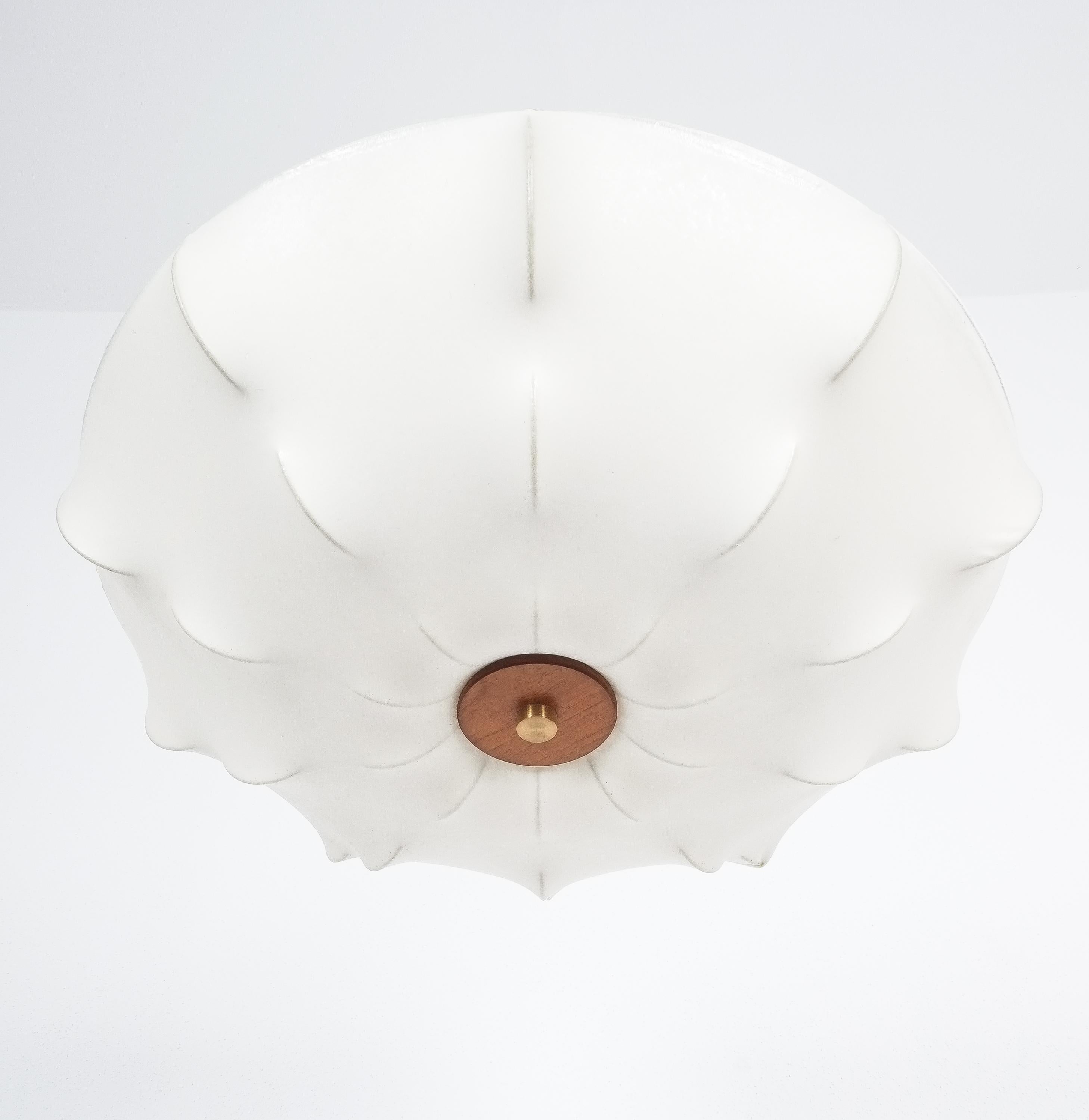 Midcentury white resin cocoon flush mount, Italy, circa 1970

Very well preserved biomorphic flush mount lamp. The lampshade is made of a cocoon type fabric and the rack is made of metal. A wooden ring and a large brass screw hold the shade in