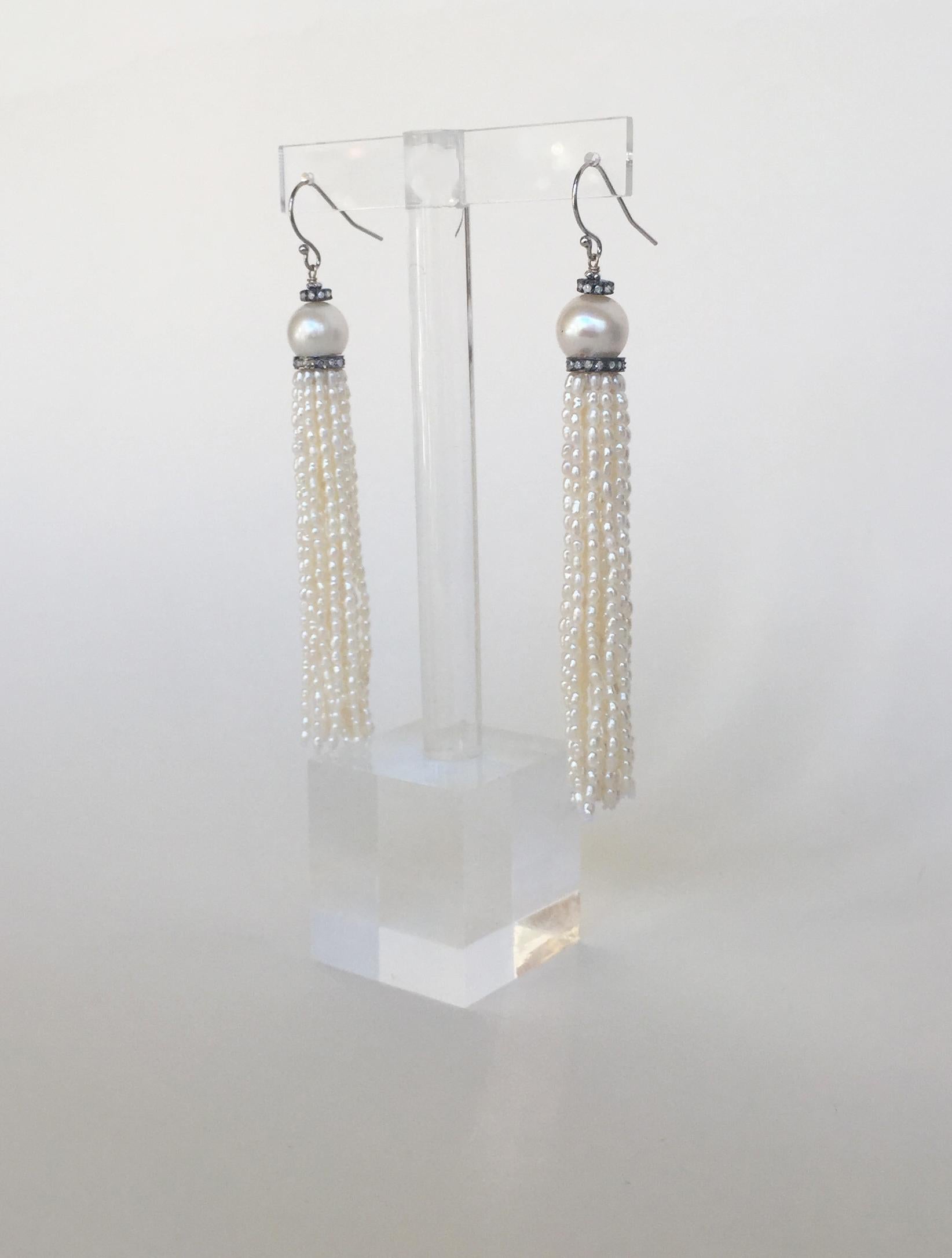 These white rice tassel earrings with diamond encrusted silver roundel and 14k white gold hooks are handmade by Marina J. These elegant tassel earrings are made with glowing white rice pearl strands. A round white pearl sits between two diamond