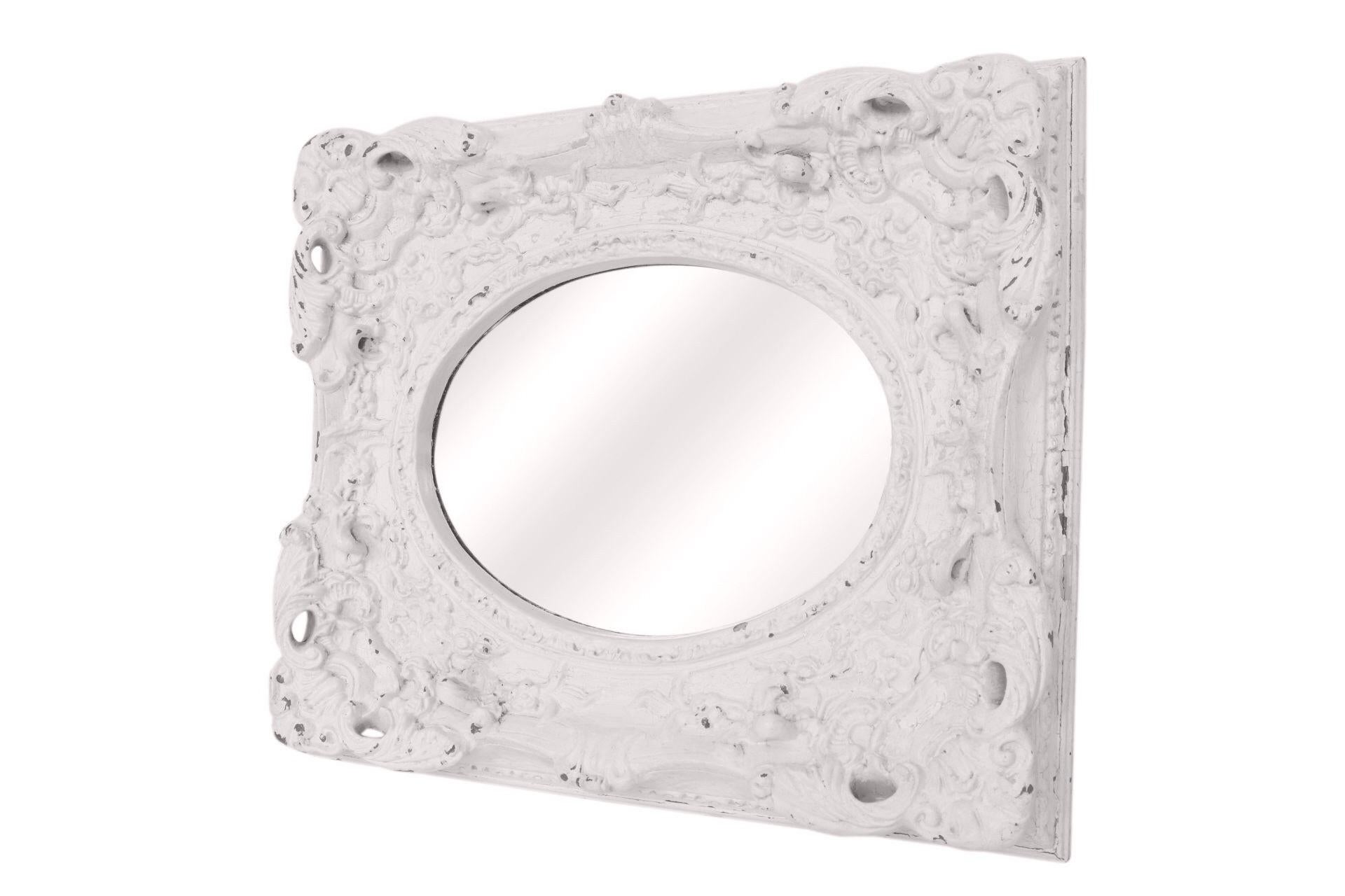 An oval mirror set in a thick, ornately carved, rococo frame painted white. Wired and ready to hang.