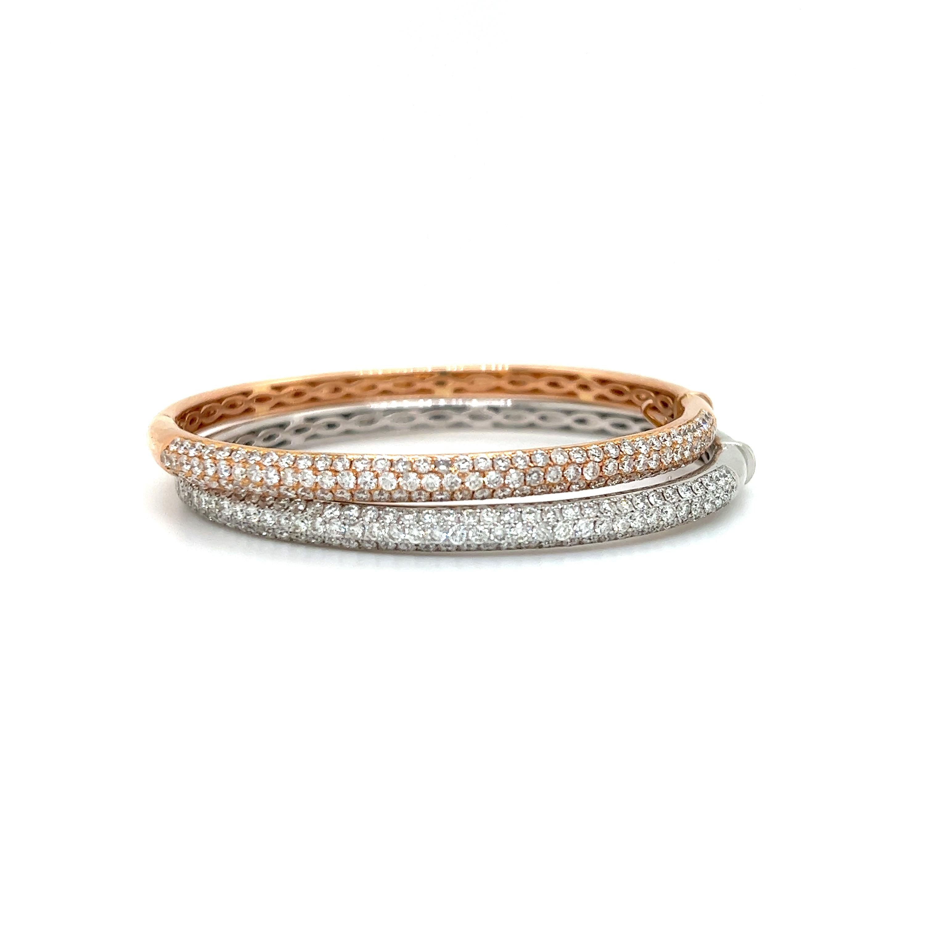 Amazing pair of white and yellow gold 18k diamond bangle bracelets. The pair are set with earth mined natural round brilliant cut diamonds. The diamonds are set in a three row pattern encompassing the top half of the design.  The bangles together