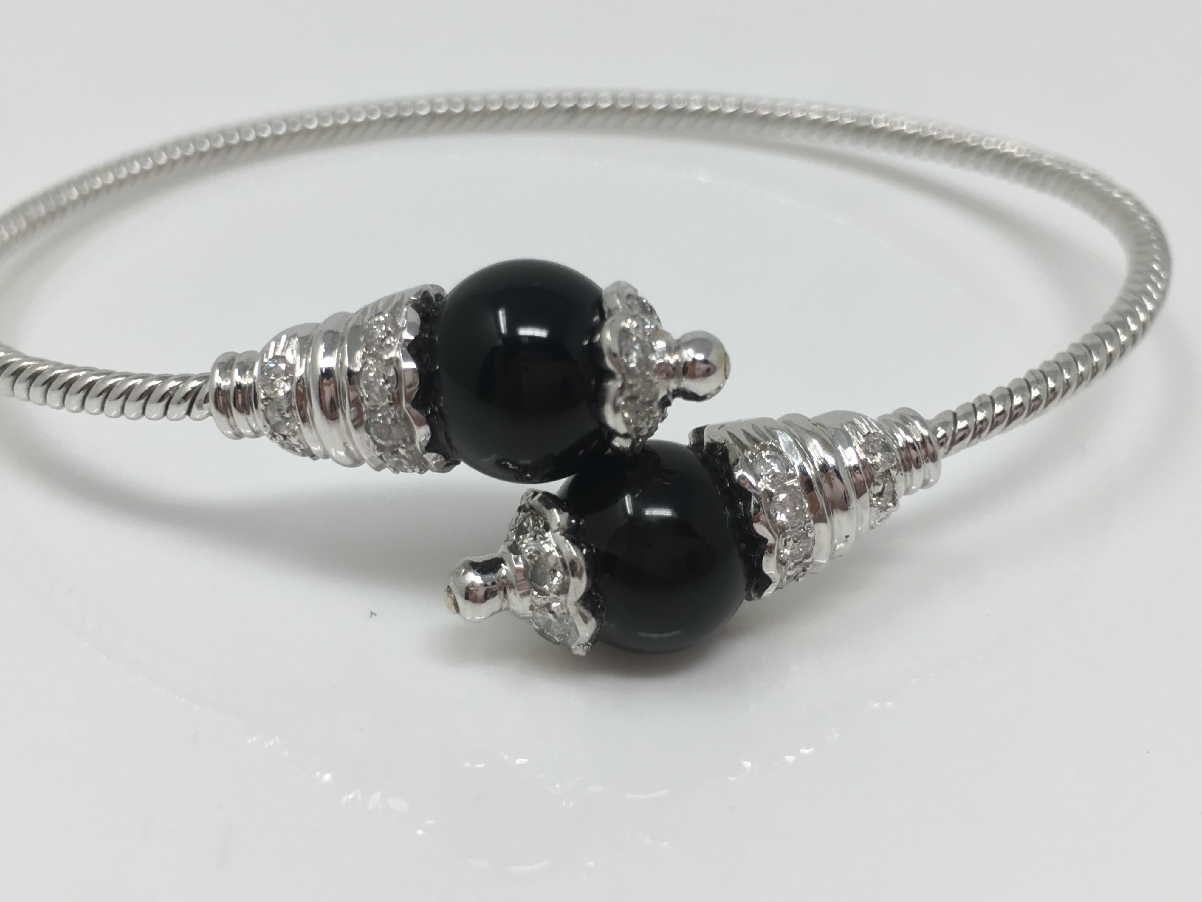 This stylish, trendy and fashionable bangle is handmade in 18K white gold by Moguldiam Inc. This bangle features white round brilliant diamond weighing 0.75 carat with GH color snd VS clarity and Onyx measuring 8.9 mm each. The bangle is flexible