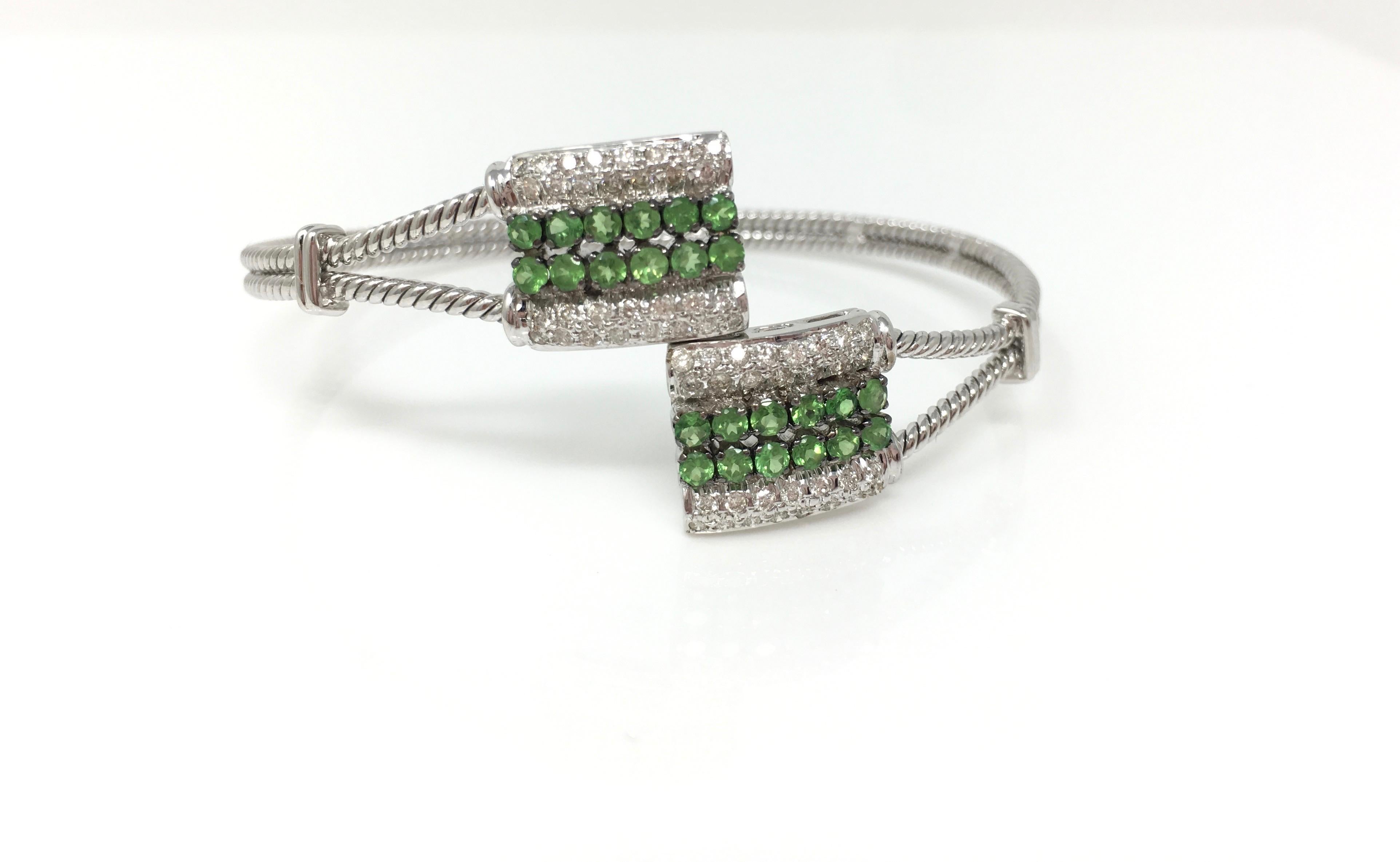 Very fashionable and chic perfect for everyday wear. An 18k white gold crossover flexible bangle bracelet with pave set white round brilliant diamond weighing 0.61 carat with VS clarity GH color and round brilliant tsavorite weighing 1.17 carat.