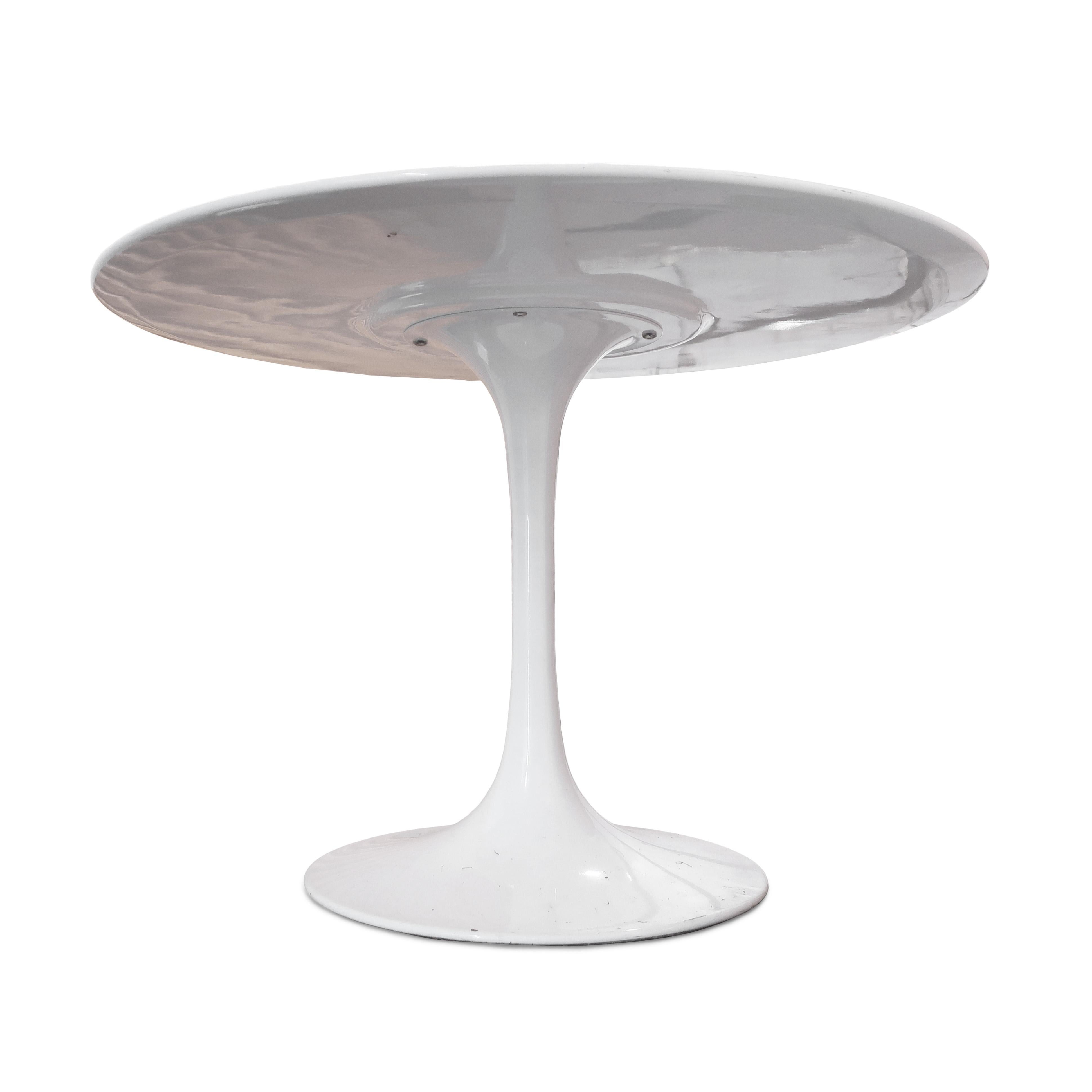 An instantly recognizable and iconic dining table featuring white powder coated tulip base and white lacquer top designed by mid-century modern superstar Eero Saarinen for Knoll in the 1950s. The table top features a beveled edge sitting on a single